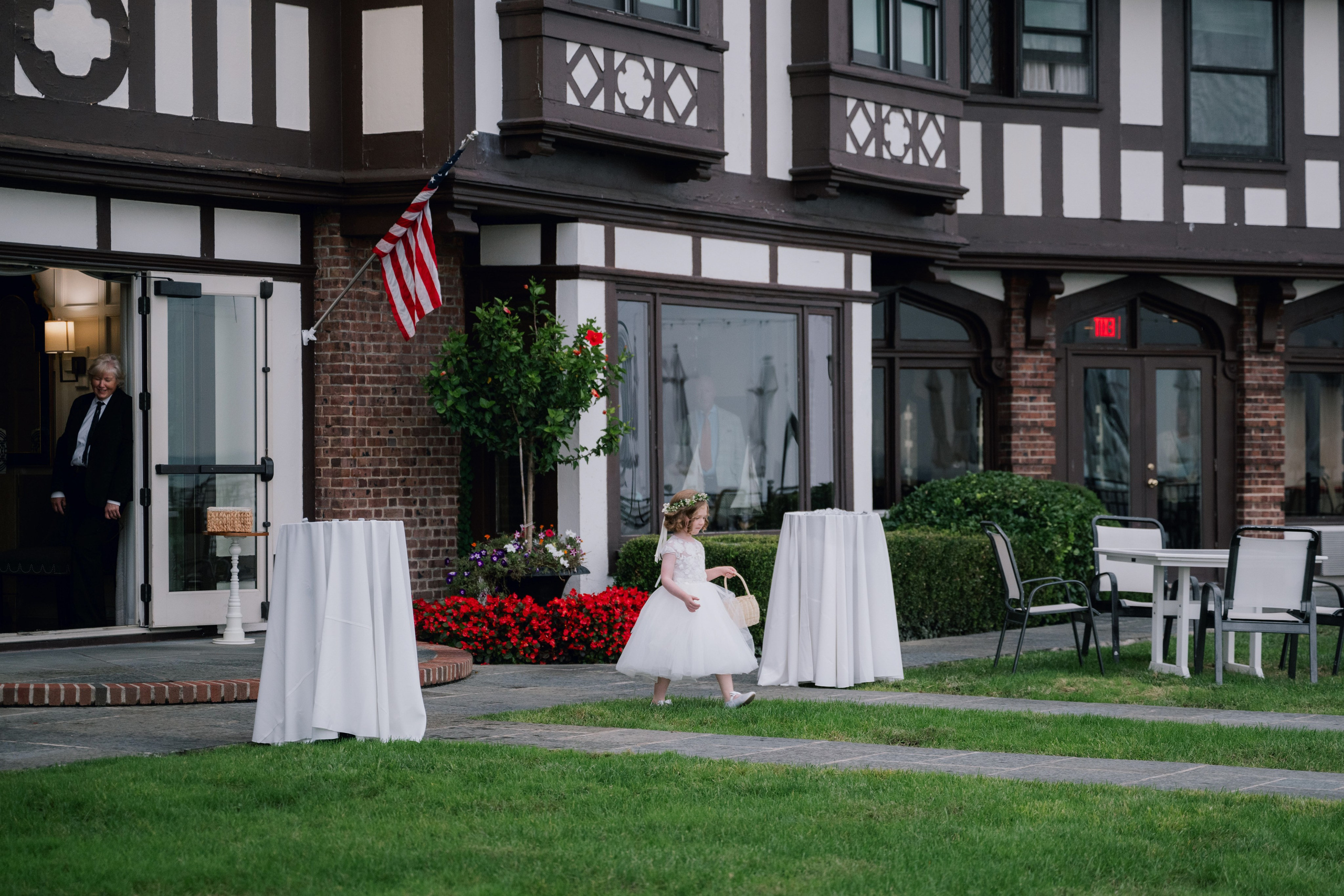 a little girl in a white dress is standing in front of a house