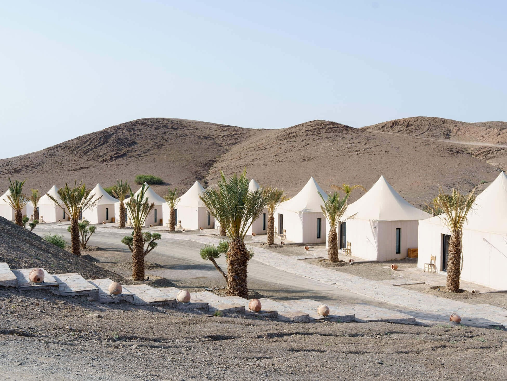 Desert wedding guest tents arranged beside palm trees, Morocco