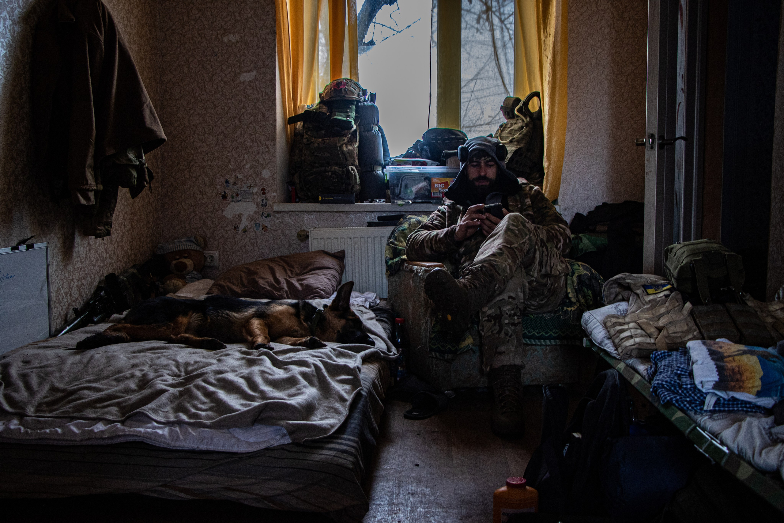 Un militaire se reposant et attendant les ordres avec son chien dans une maison réquisitionné après les affrontements dans la région de Kherson.