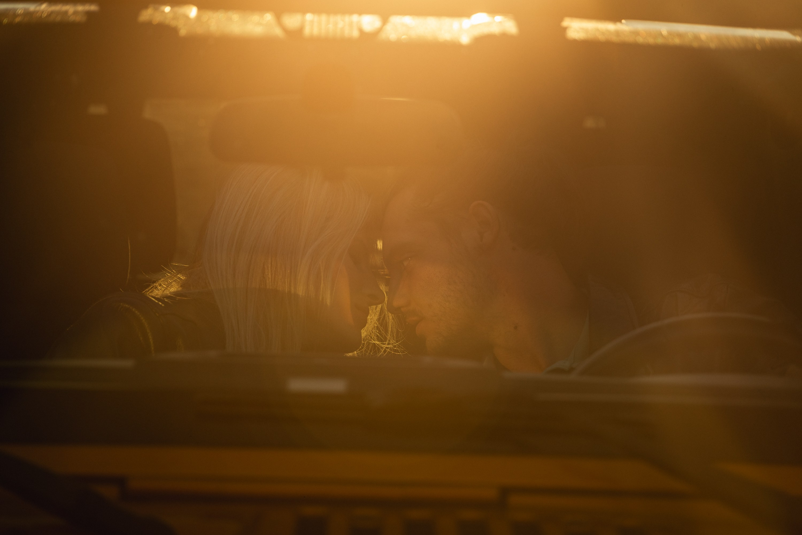 The couple's tender kiss through the car window captures a heartfelt, romantic journey moment.