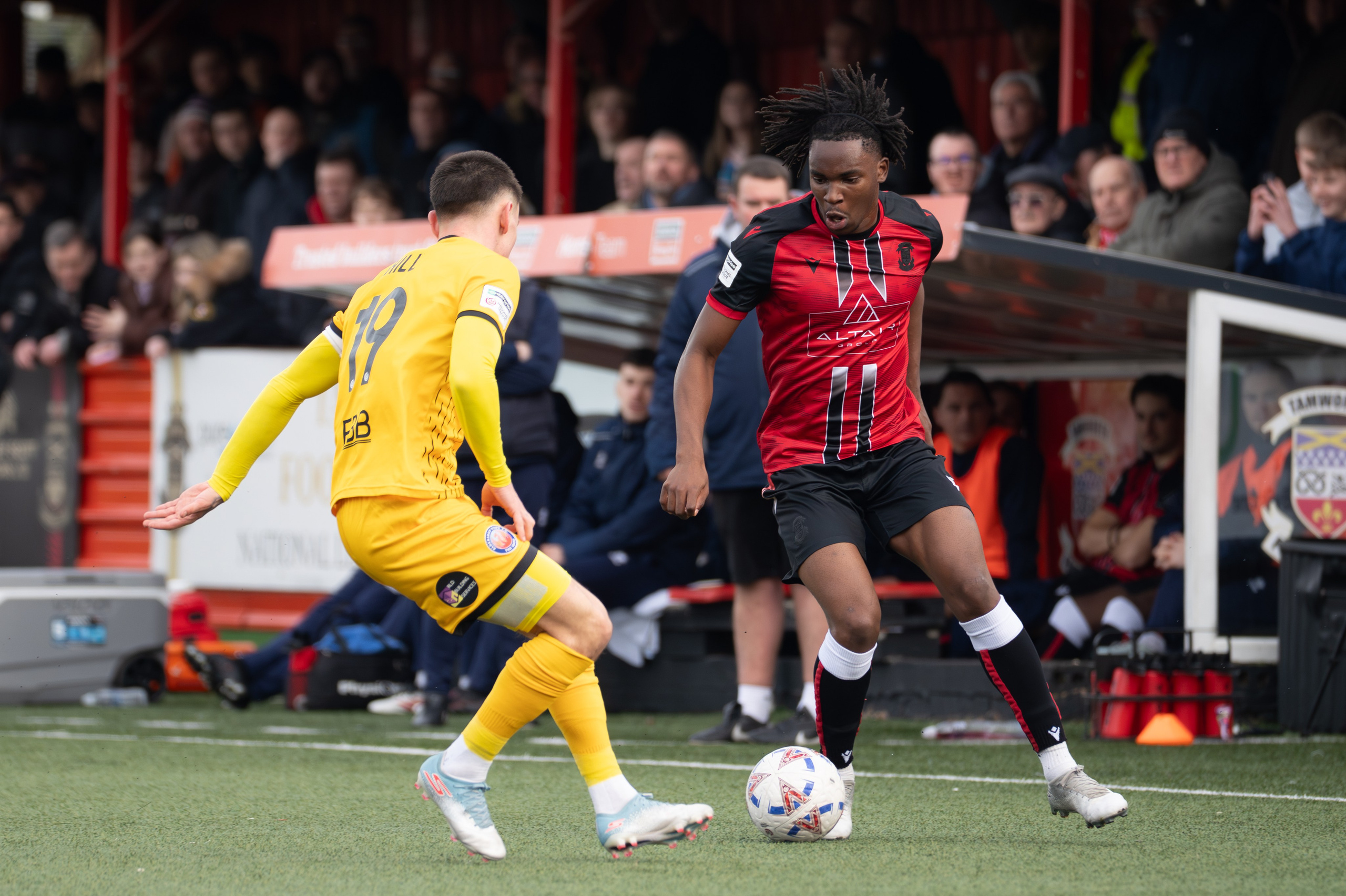 Tamworth, England — February 14, 2026: Tamworth FC’s Daniel Isichei controls the ball under pressure from an Aldershot Town player during the Enterprise National League match between Tamworth FC and Aldershot Town at The Lamb Ground. Photo: Jay Soundo