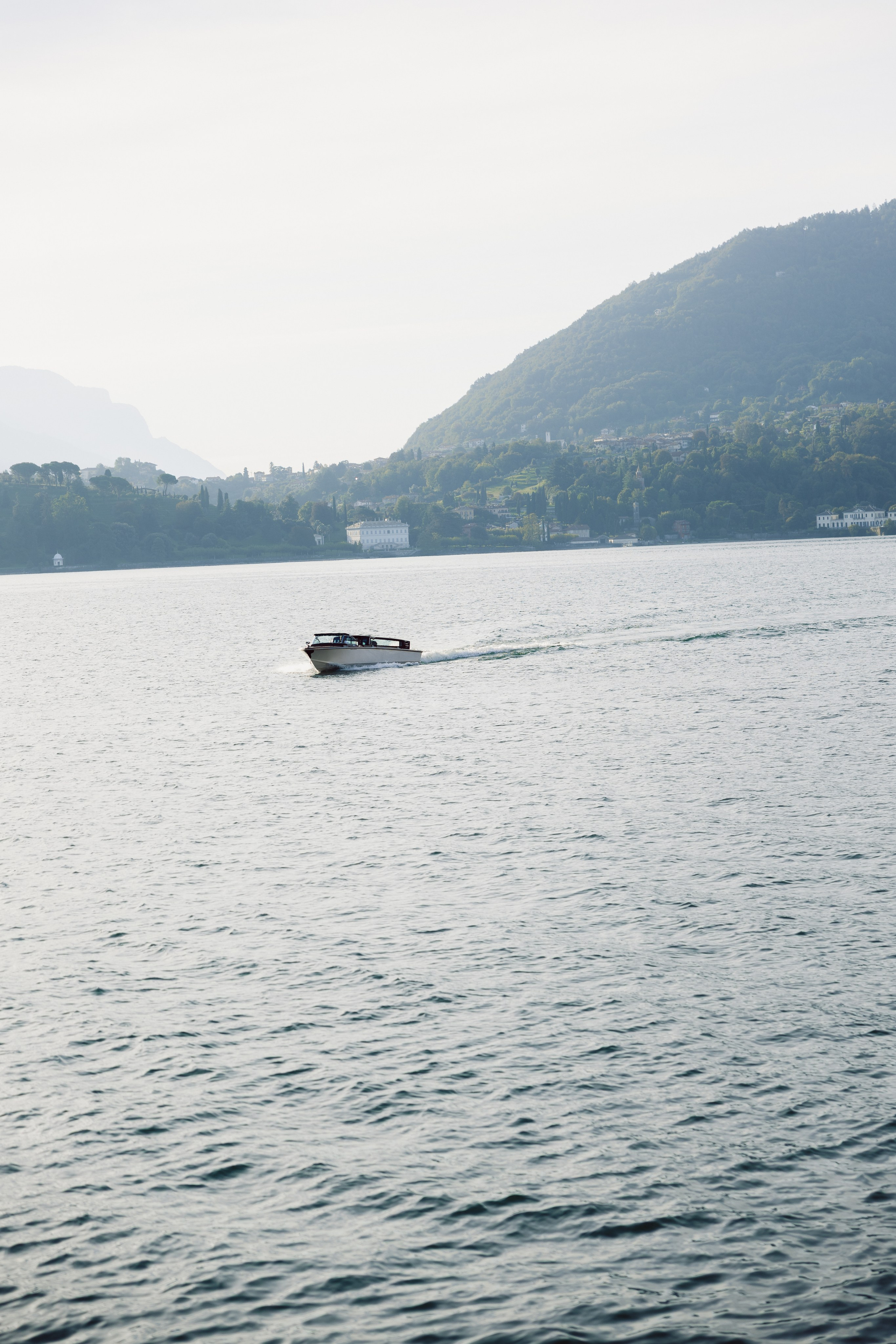 Motorboat crossing Lake Como with mountain scenery in the background