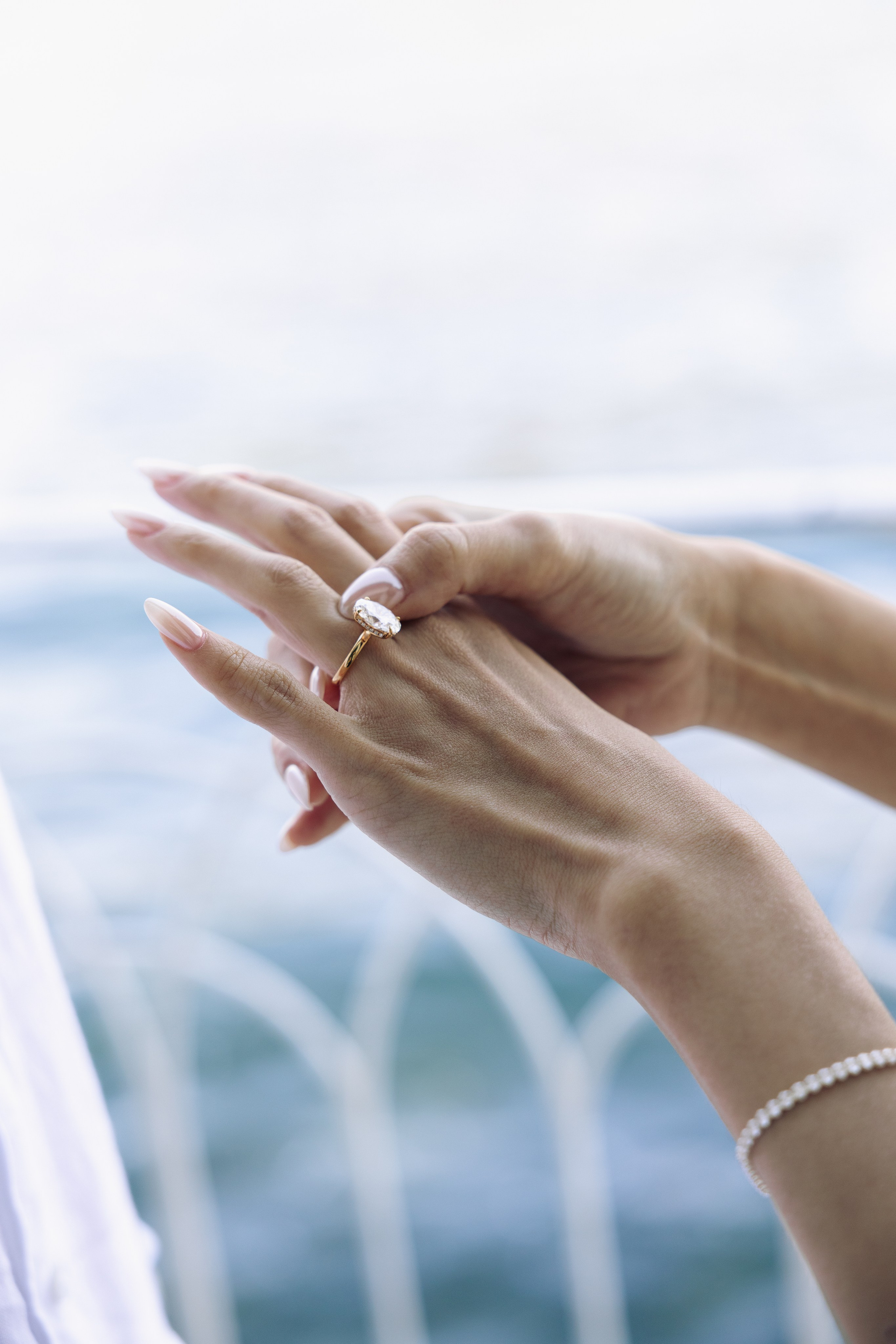 Close-up of a diamond engagement ring with Lake Como in the background