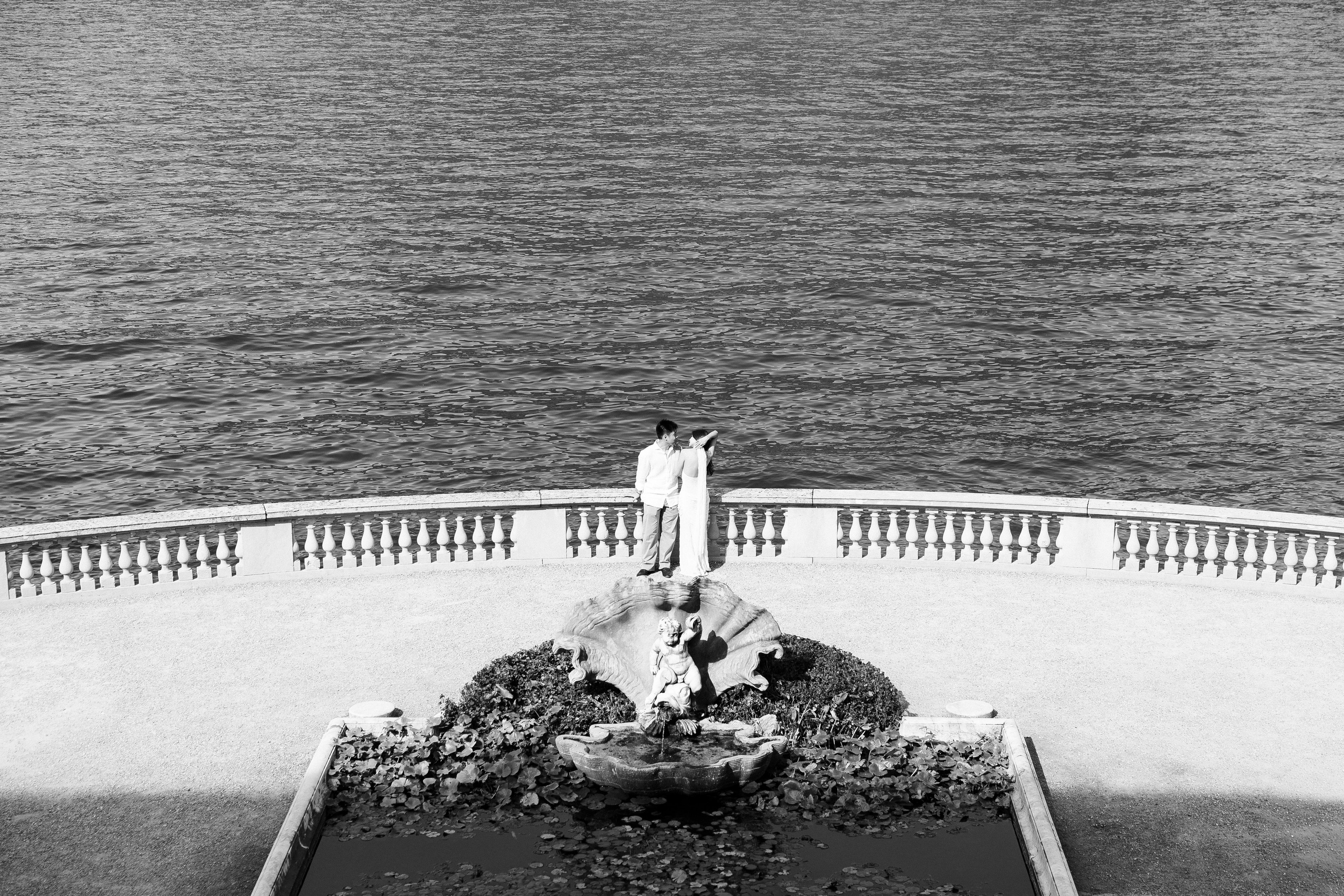Black and white view of a couple on the lakeside terrace at Villa Melzi Gardens, Lake Como
