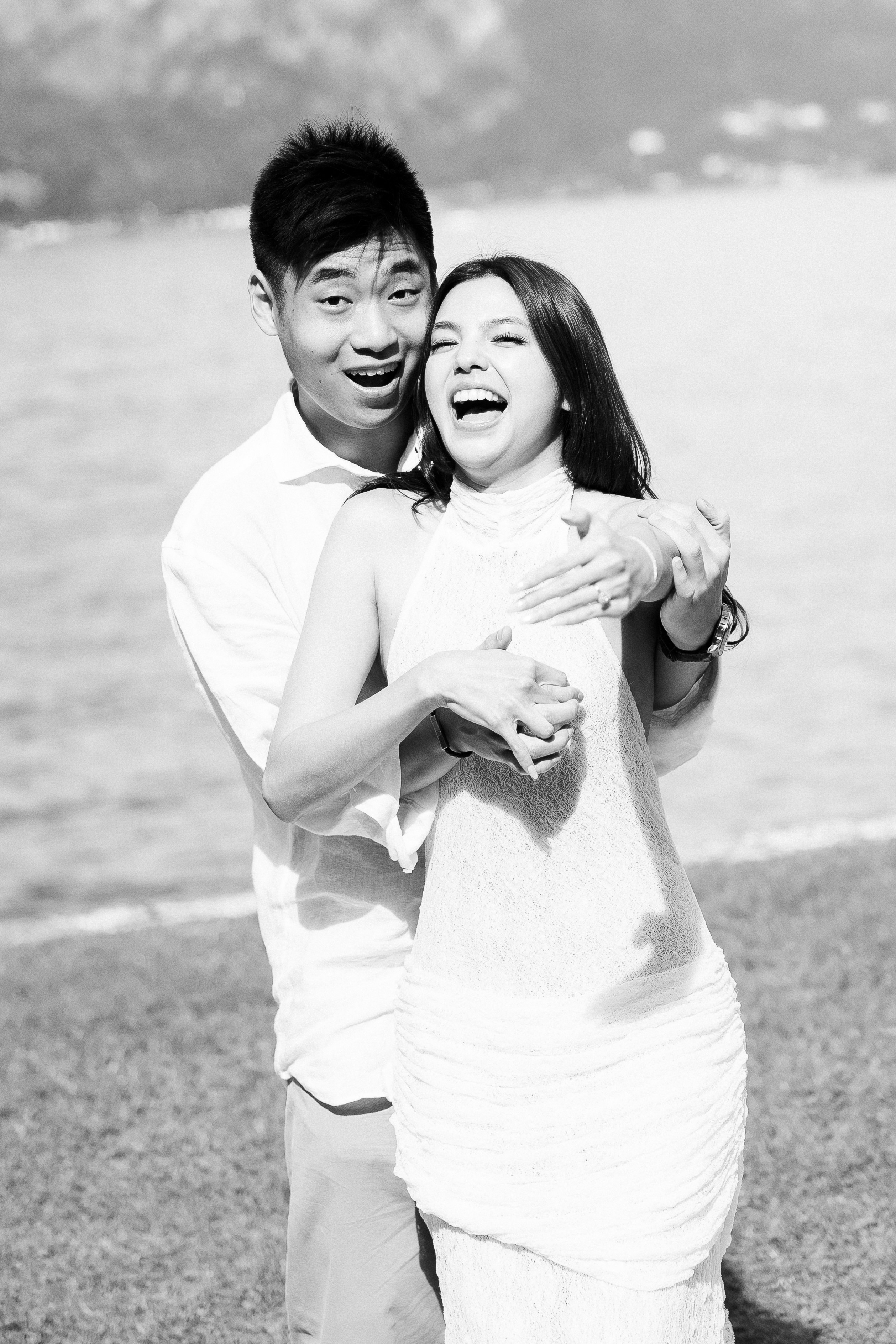 Black and white portrait of a couple laughing together by the shores of Lake Como.
