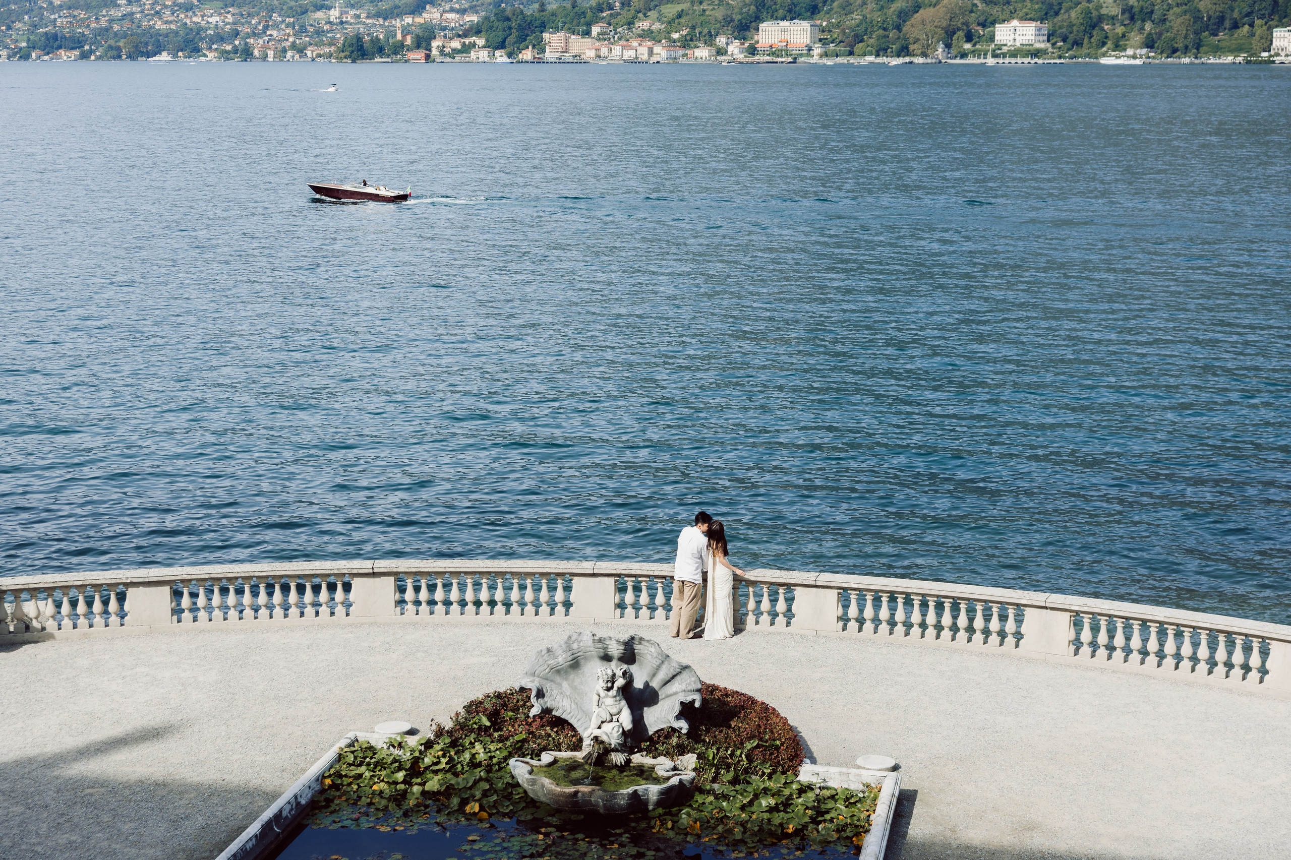Couple embracing beside an ornamental fountain on the waterfront terrace of Villa Melzi, Lake Como.