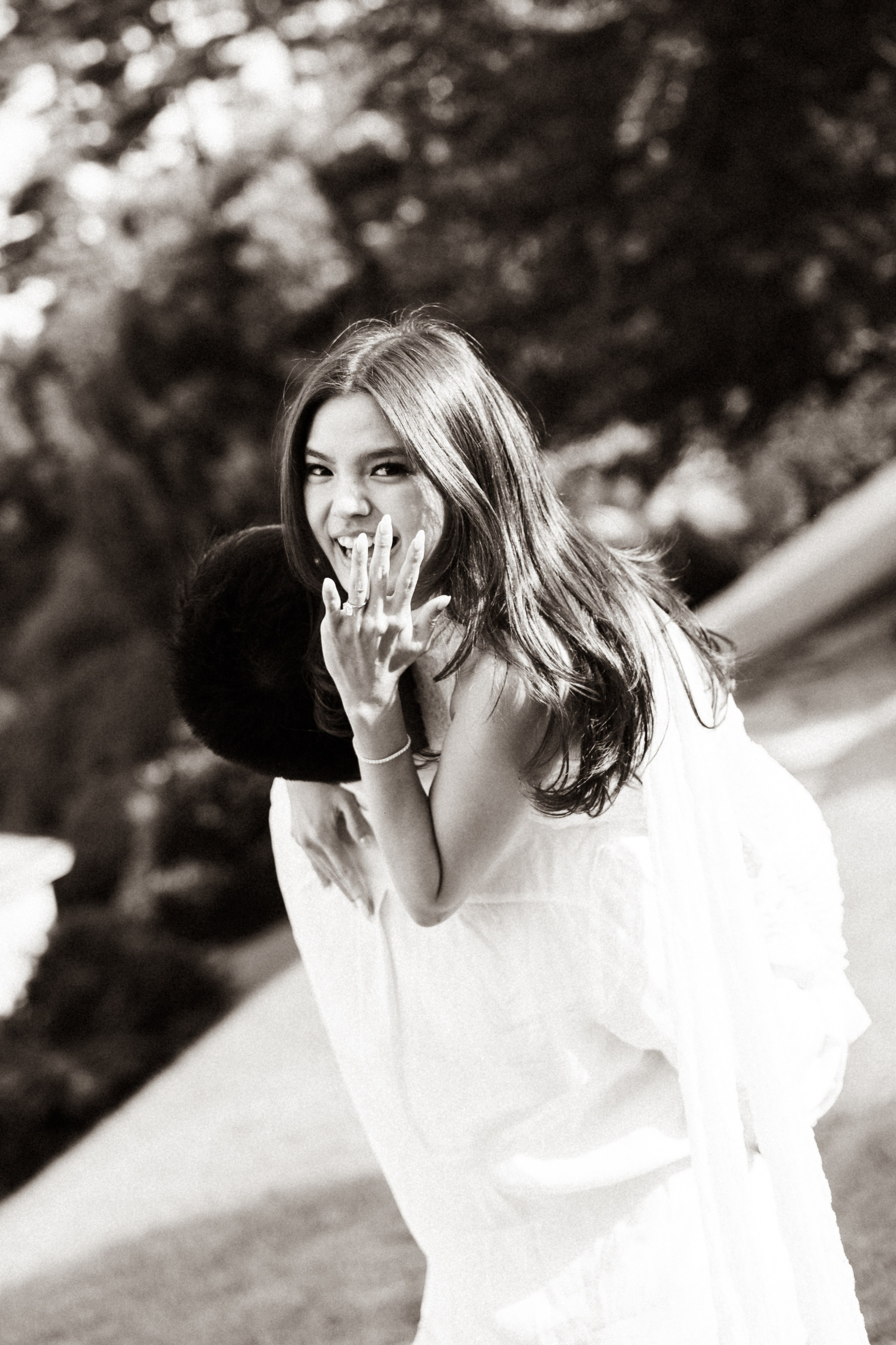 Black and white candid portrait of a woman smiling and covering her mouth during a romantic Lake Como session.