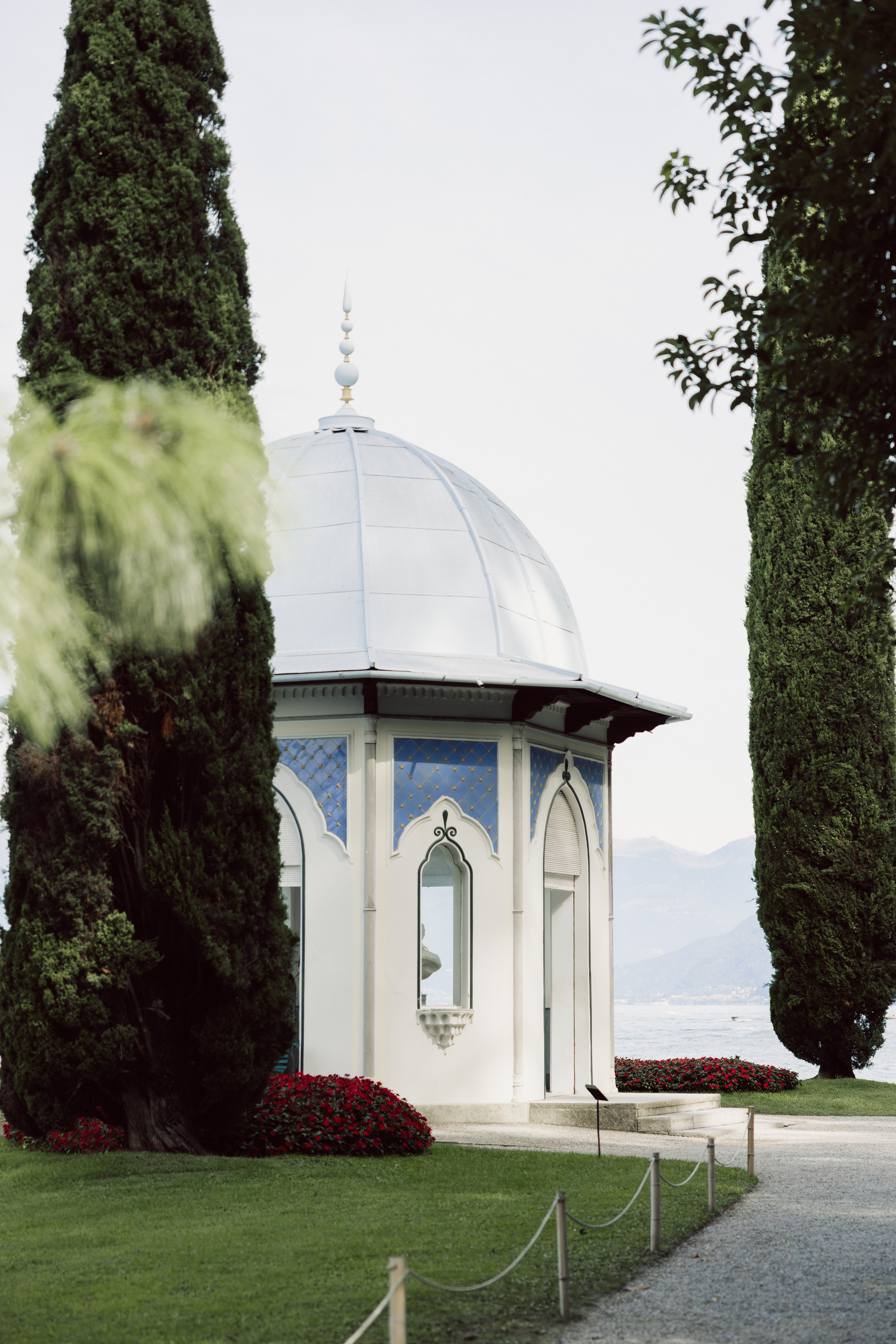 Decorative lakeside pavilion surrounded by cypress trees in Villa Melzi Gardens
