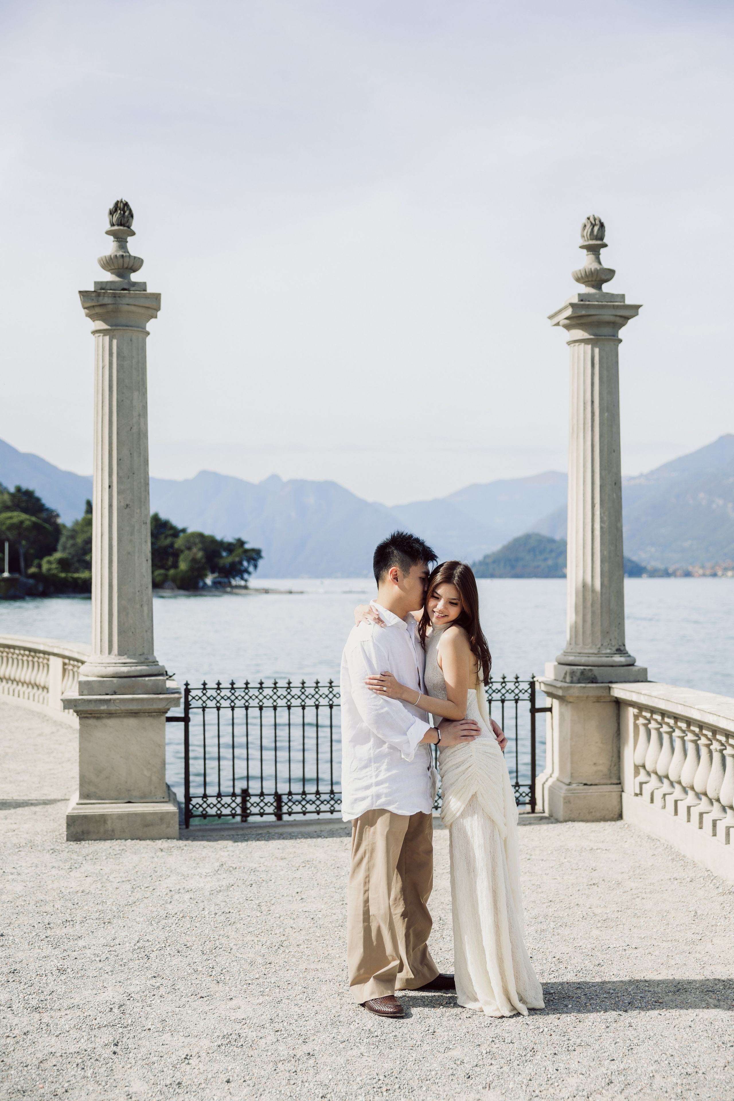 Couple embracing between stone columns on the Villa Melzi lakeside terrace
