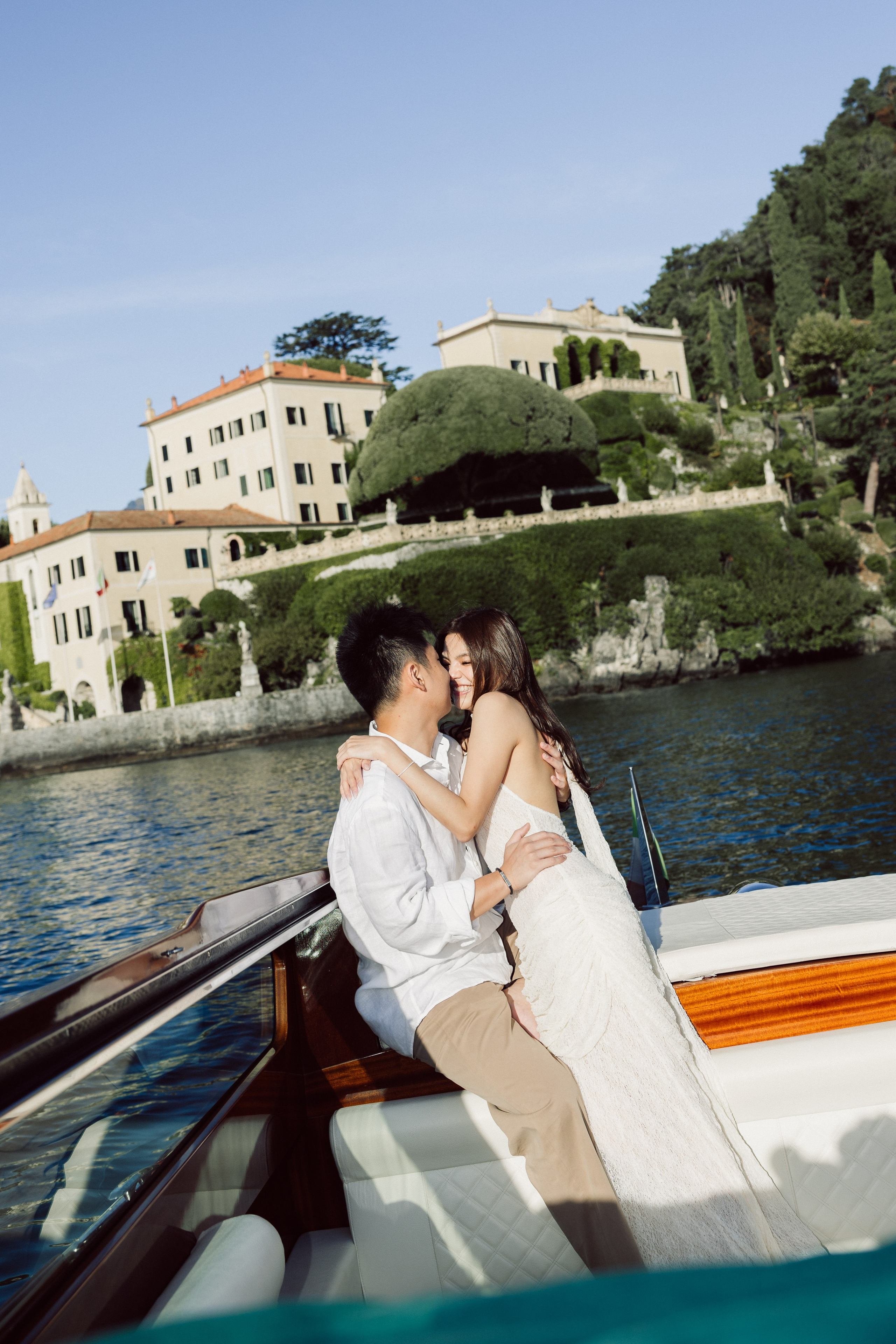 Couple kissing on a private wooden boat during a romantic Lake Como photoshoot