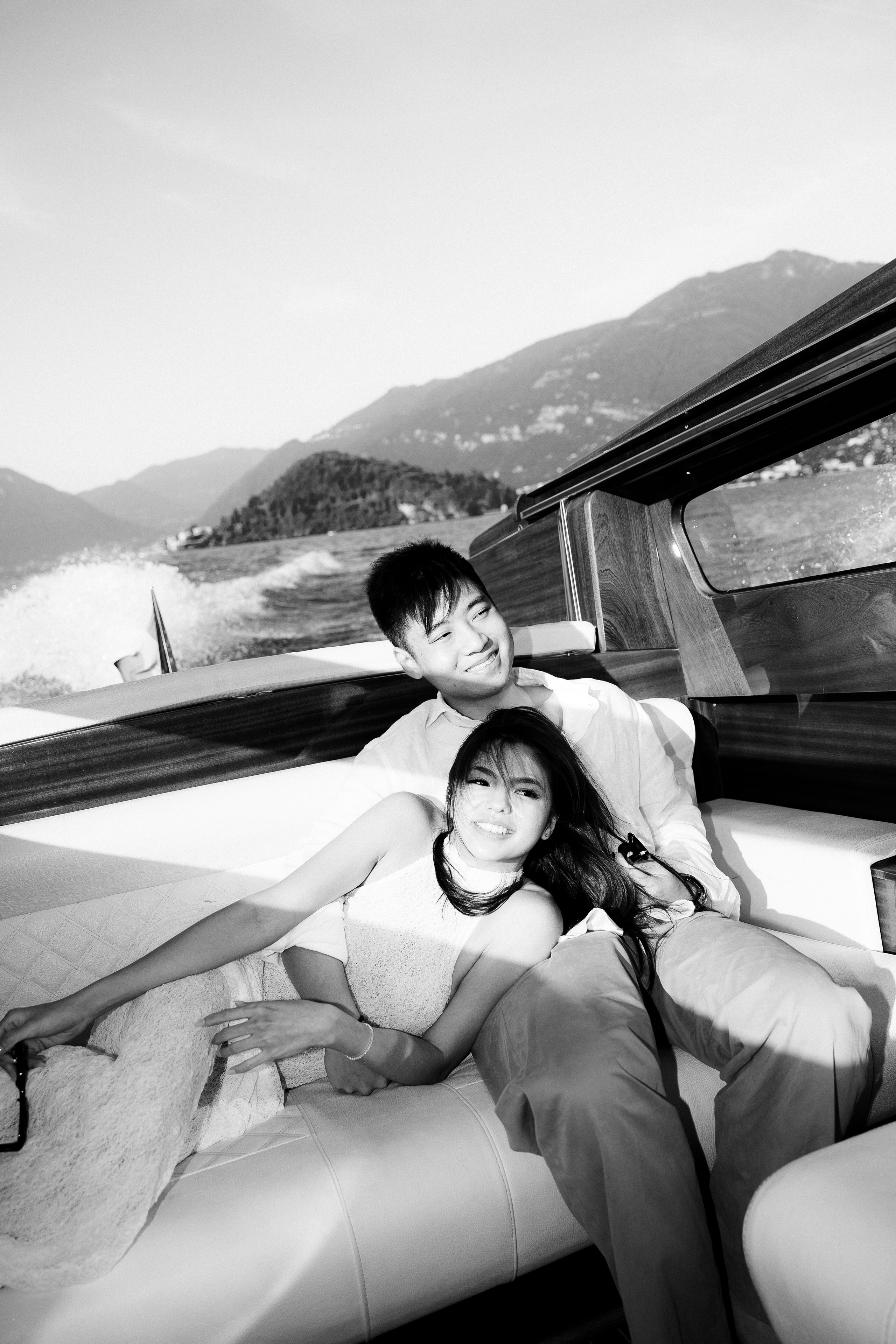 Black and white portrait of a smiling couple relaxing together on a private boat on Lake Como.