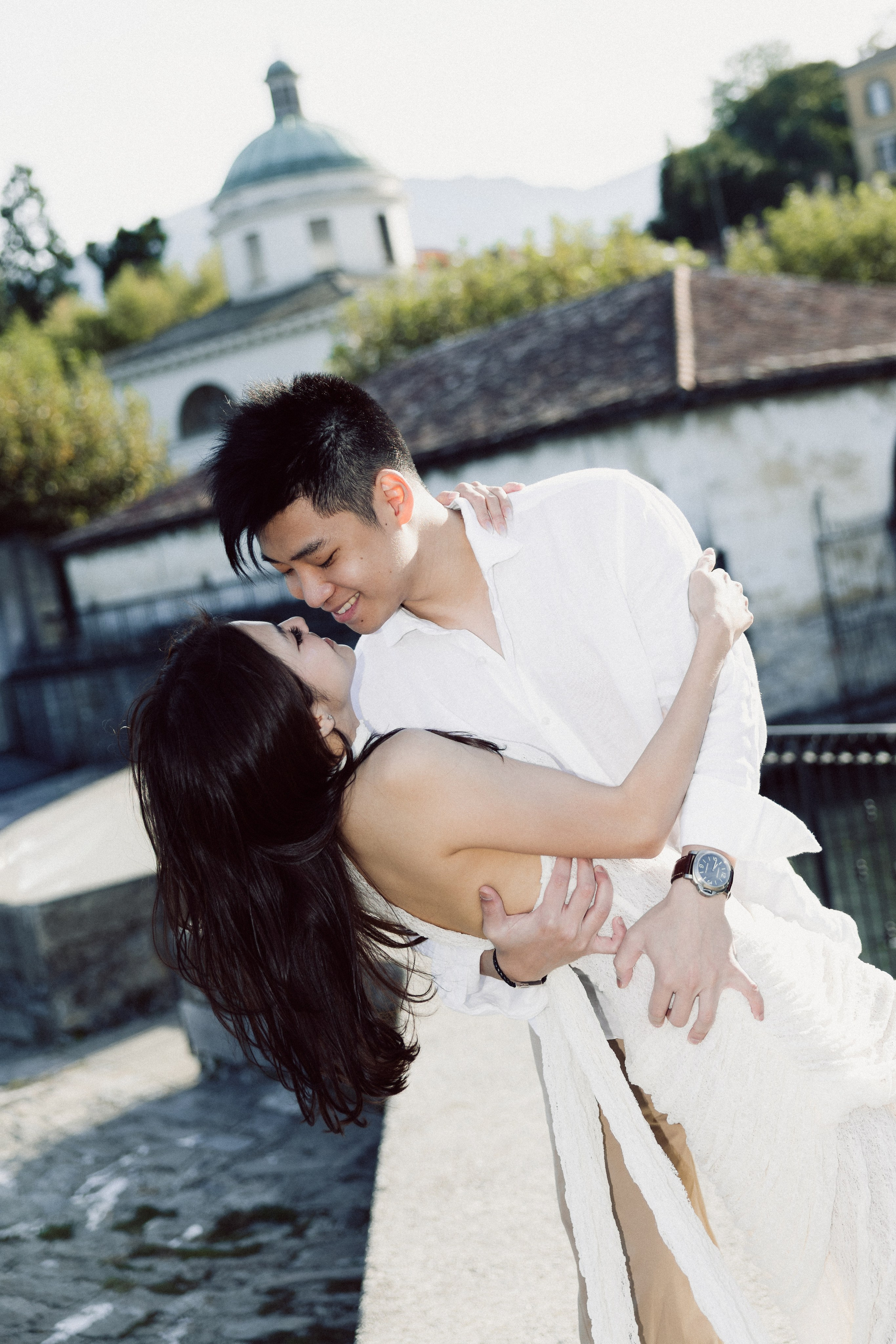 Man playfully dipping his partner during a romantic moment by the waterfront in Bellagio.
