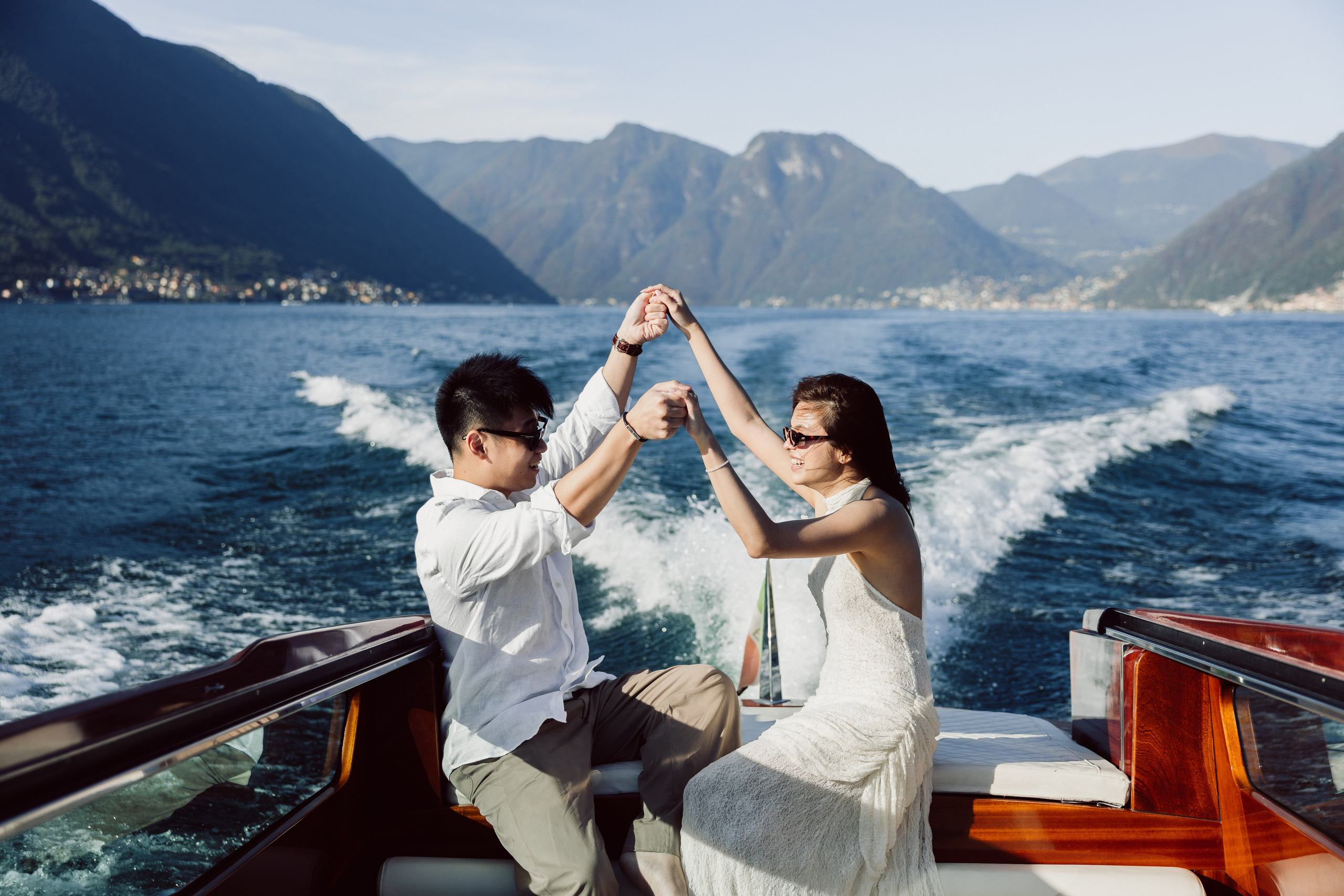 Newly engaged couple raising their hands together during a private Lake Como boat ride