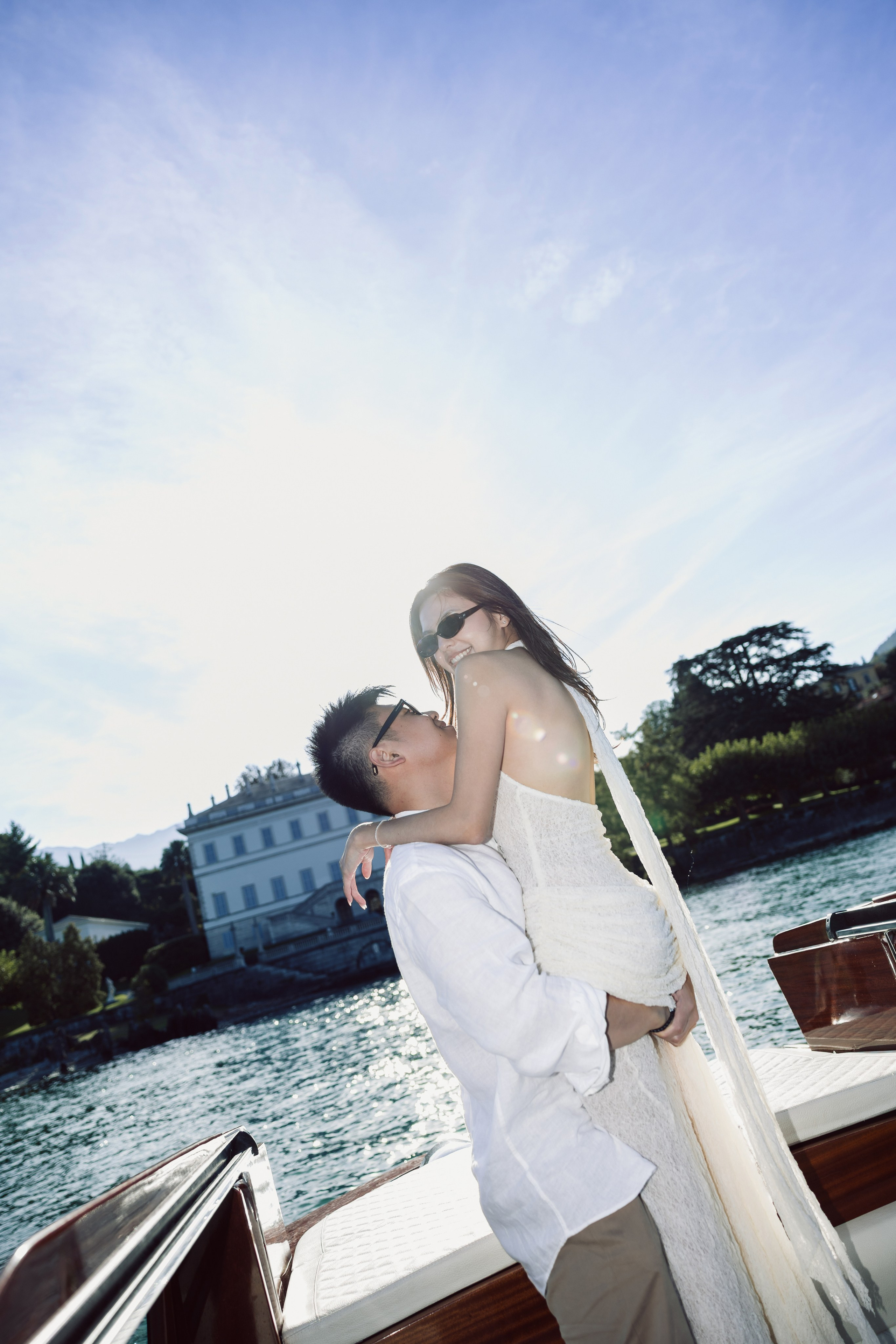 Man lifting his partner during a joyful romantic boat photoshoot on Lake Como