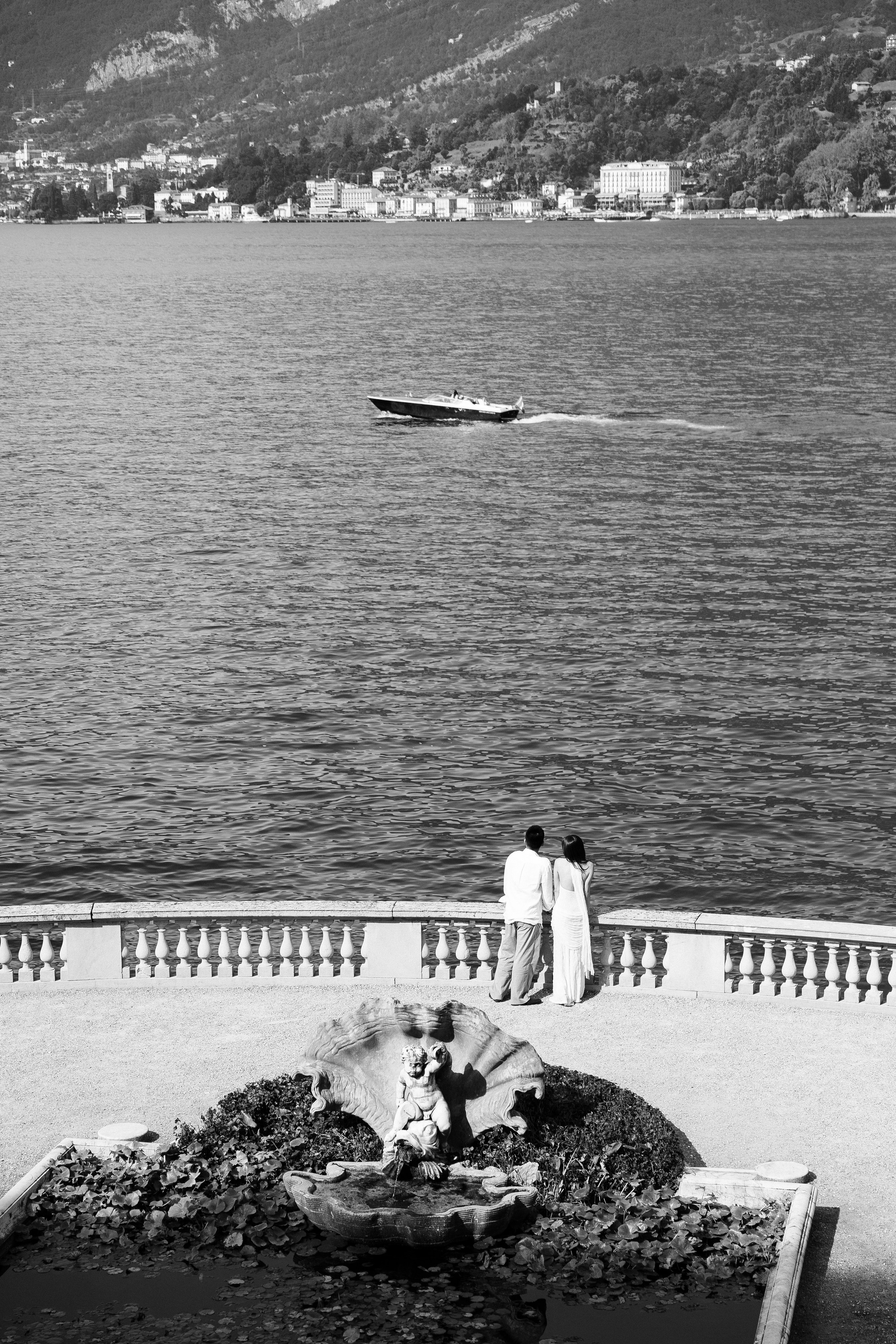 Black and white portrait of a couple laughing and embracing beside Lake Como