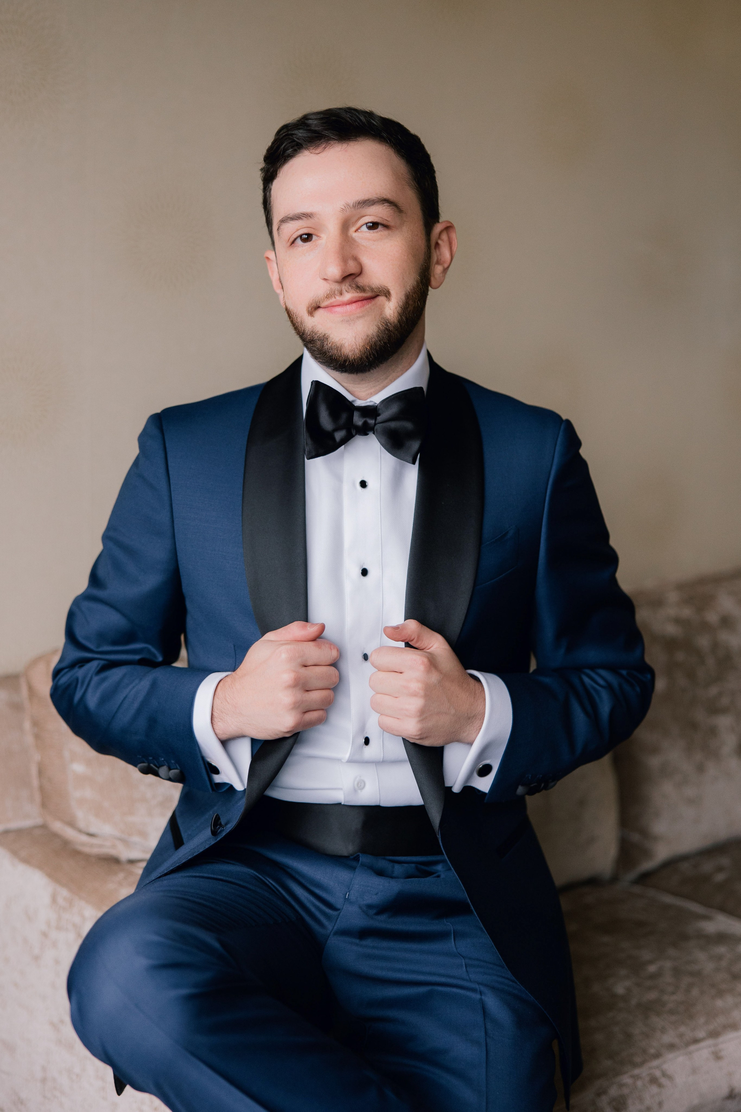 a man in a suit and bow tie sitting on a couch