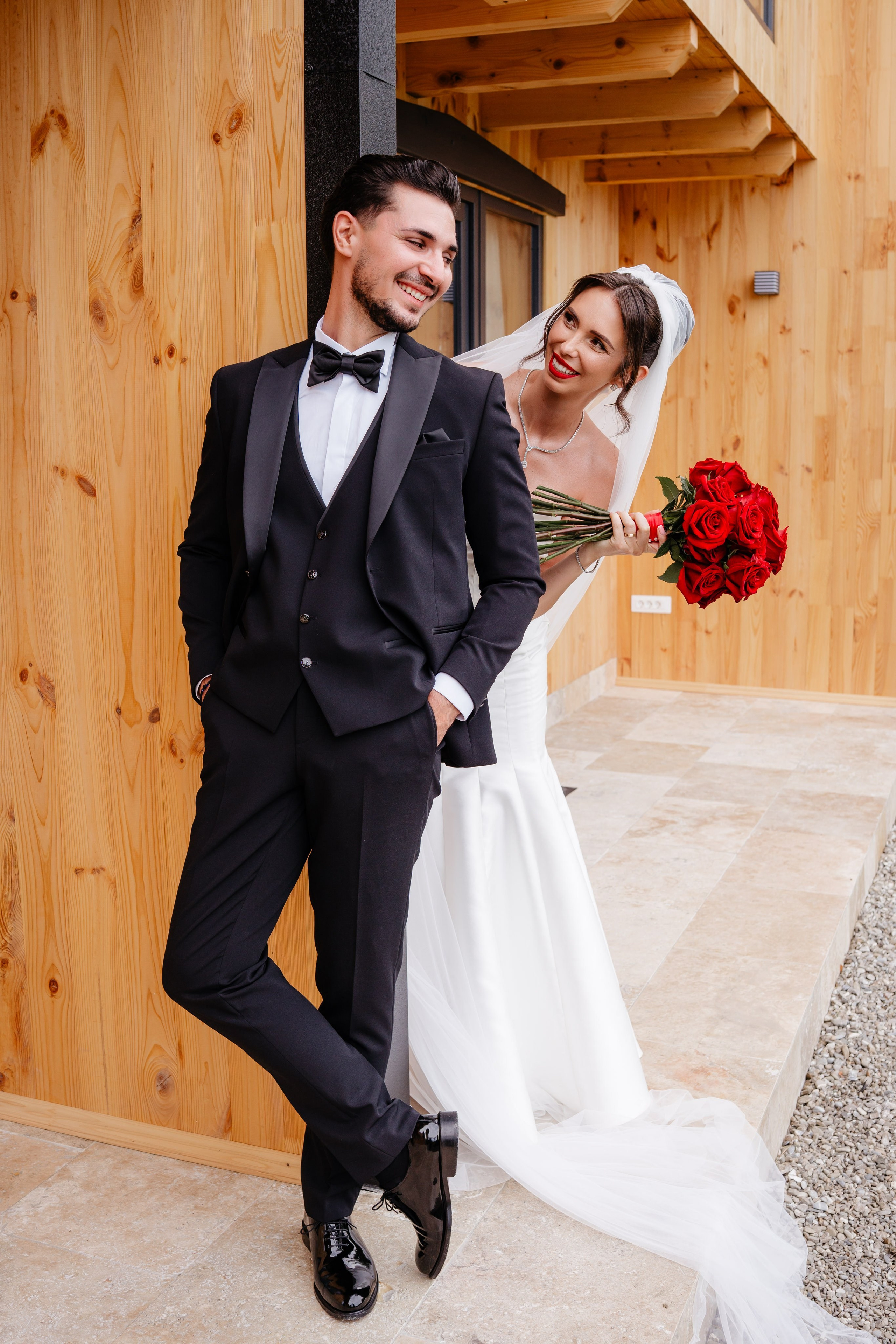 Anca și Dragoș pozând cu buchetul de trandafiri roșii în decorul cabanei.