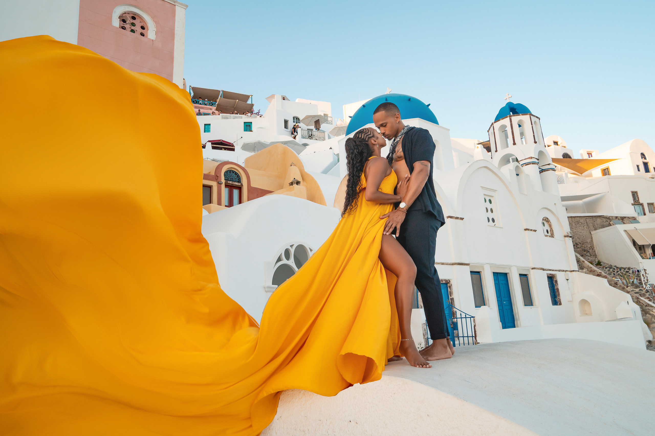 Amour et Lumière: Séance Photo d’un Couple au Coucher du Soleil à Oia, Santorin. Photographe vidéaste à Santorin|Séances photos de Robe volante Santorin|