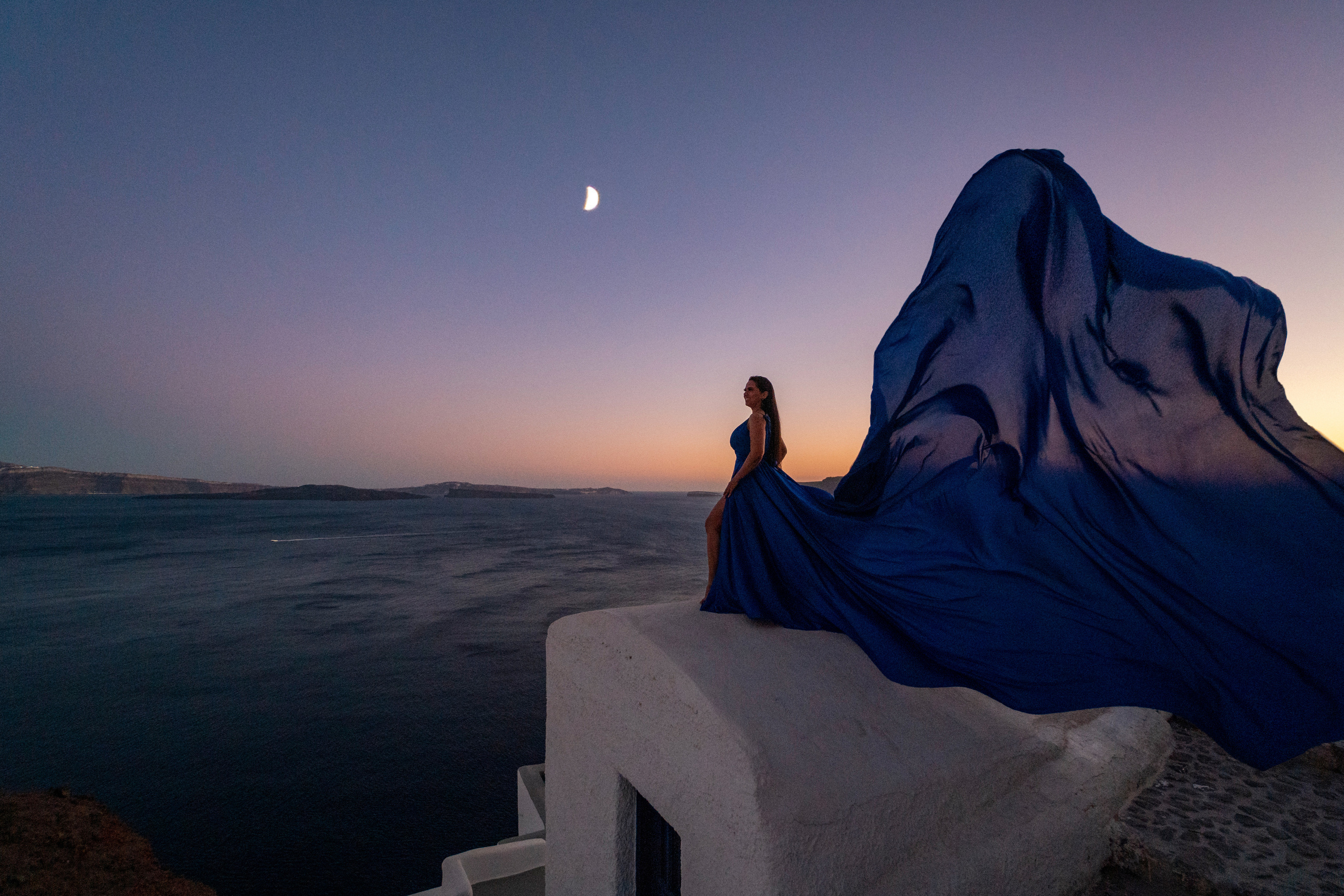 Suset in Oia blue silk flying dress. Photographer in Santorini SokoLOVE Alex| Flying Dress Santorini