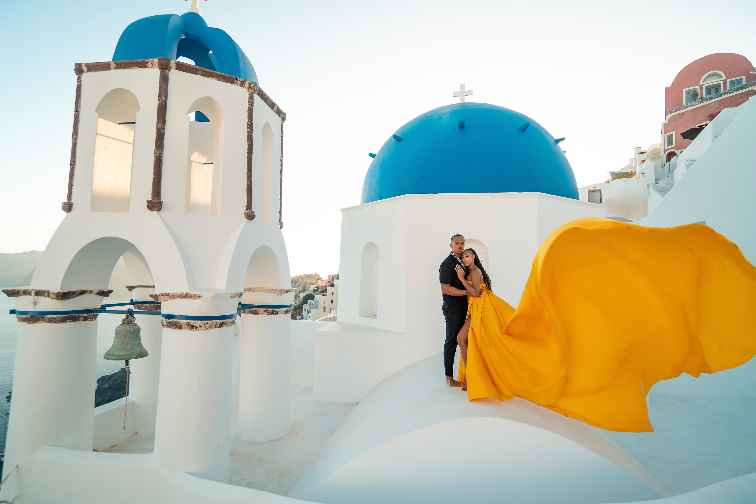 Amour et Lumière: Séance Photo d’un Couple au Coucher du Soleil à Oia, Santorin. Photographe vidéaste à Santorin|Séances photos de Robe volante Santorin|