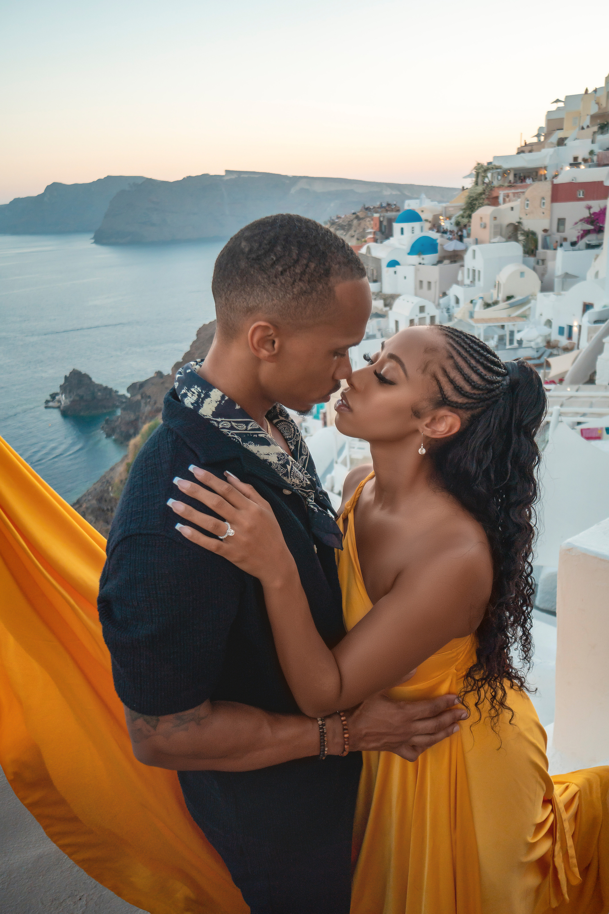 Amour et Lumière: Séance Photo d’un Couple au Coucher du Soleil à Oia, Santorin. Photographe vidéaste à Santorin|Séances photos de Robe volante Santorin|