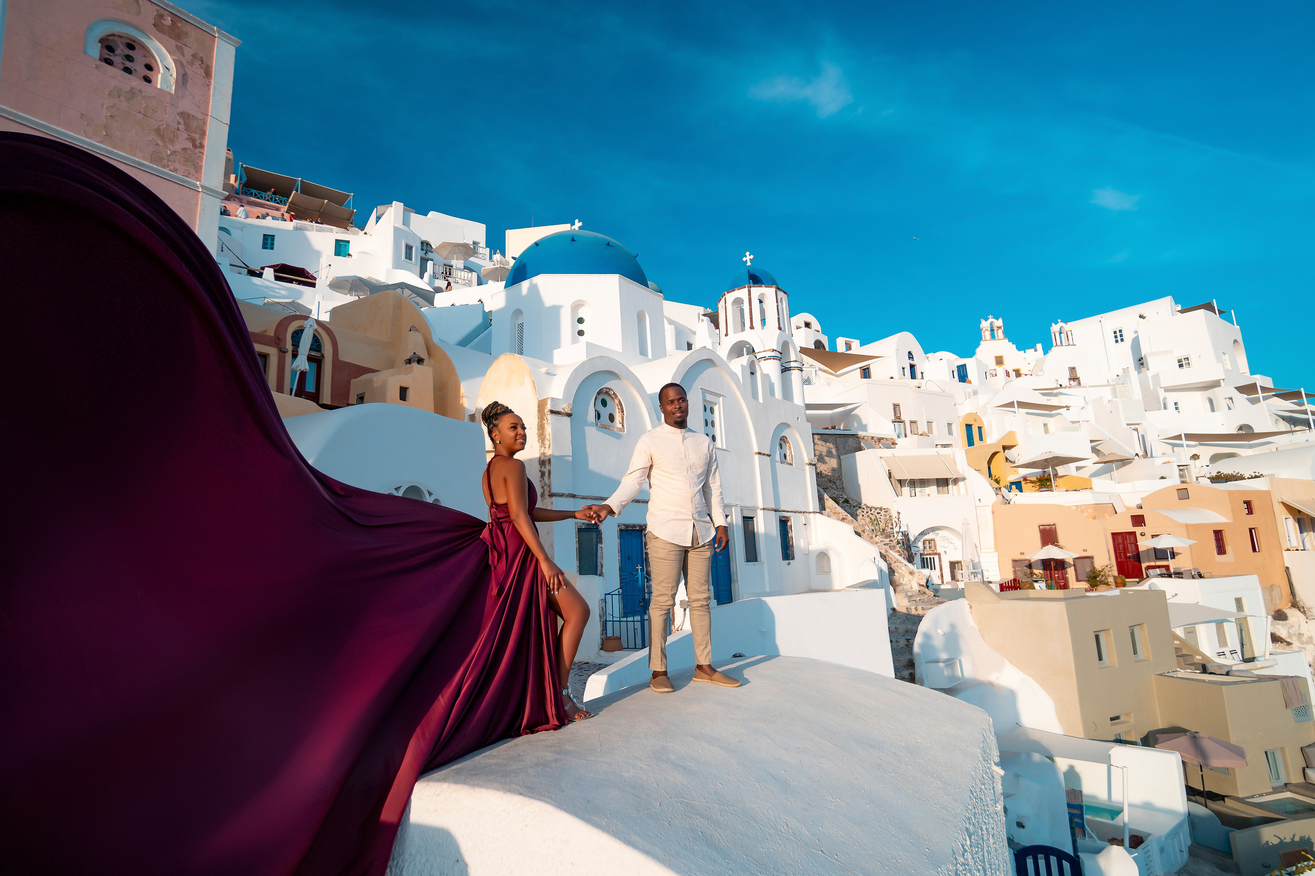 Photo session in Oia, Santorini at sunset, cherry flying dress. Photographer in Santorini SokoLOVE Alex| Flying Dress Santorini