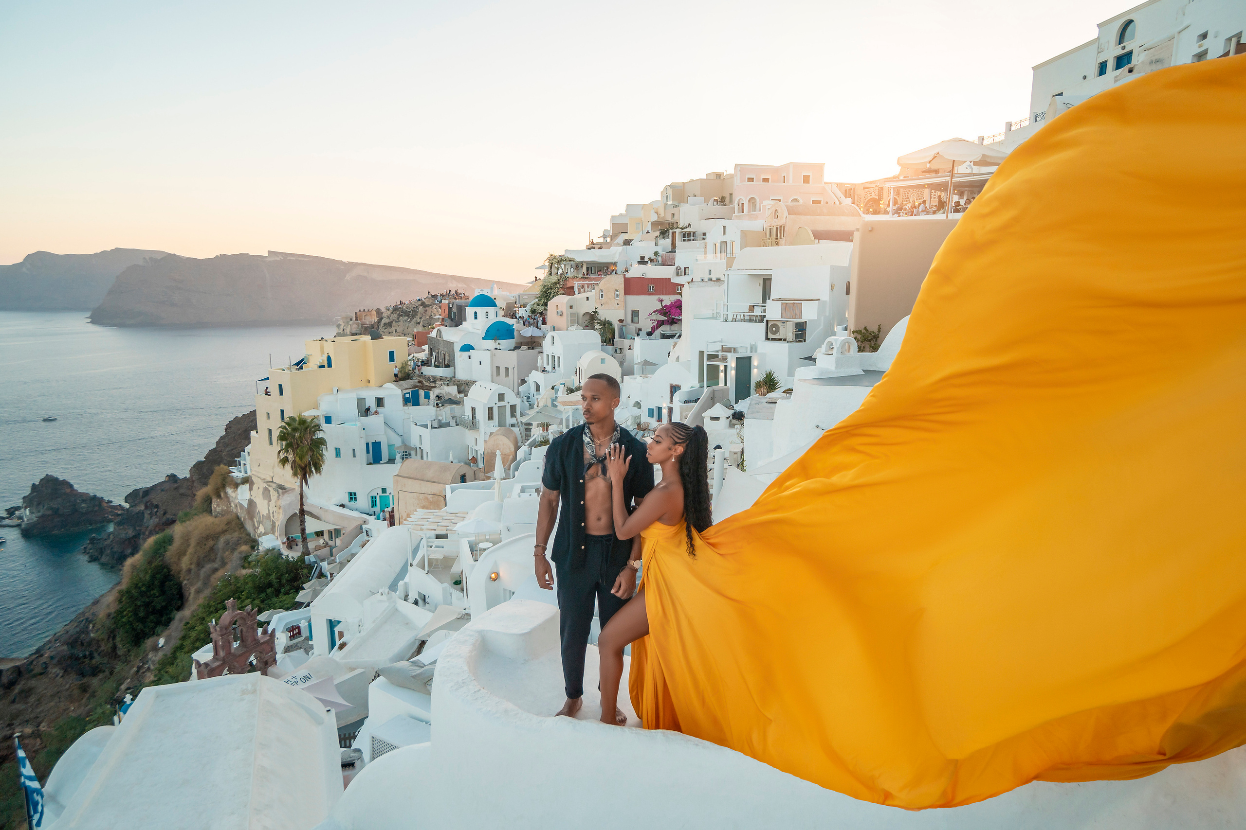 Amour et Lumière: Séance Photo d’un Couple au Coucher du Soleil à Oia, Santorin. Photographe vidéaste à Santorin|Séances photos de Robe volante Santorin|