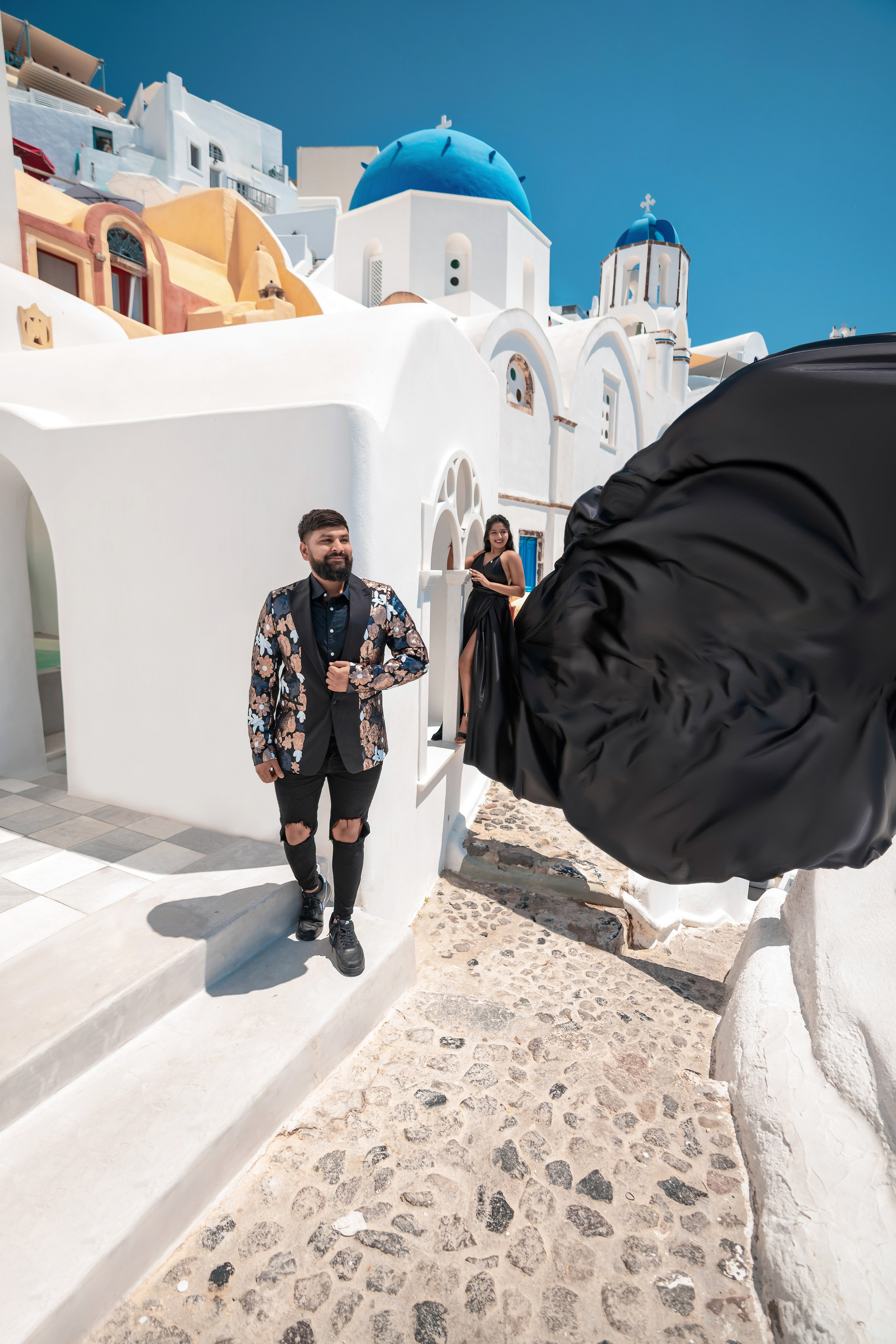 Séance photo avec une robe volante noire à Santorin: Élégance et magie intemporelles. Photographe vidéaste à Santorin|Séances photos de Robe volante Santorin|
