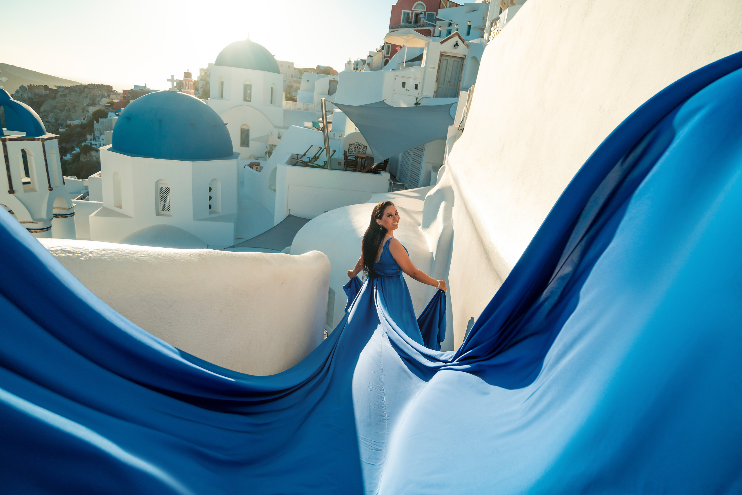 Suset in Oia blue silk flying dress. Photographer in Santorini SokoLOVE Alex| Flying Dress Santorini