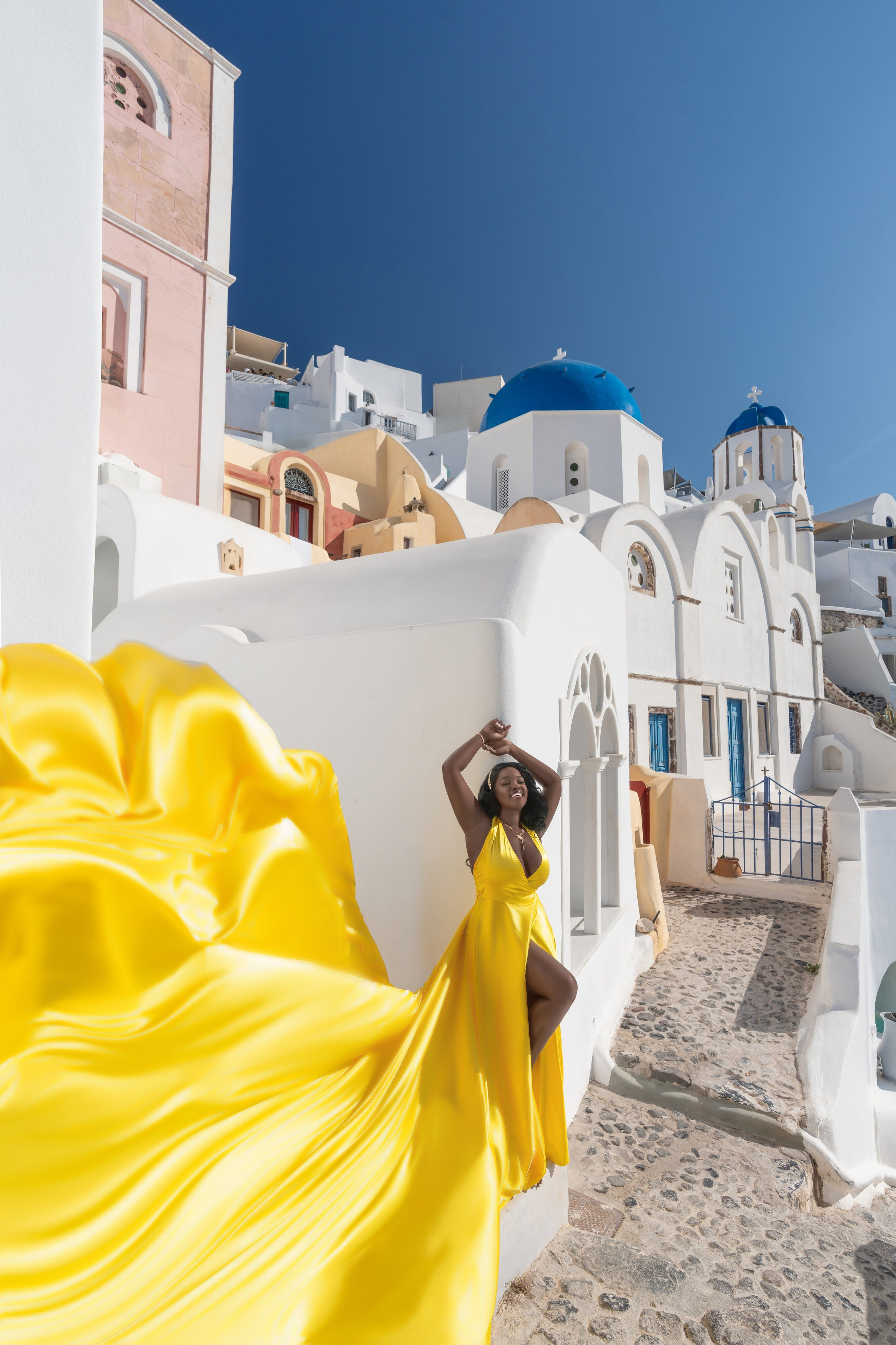 Élégance Dorée à Santorin: Séance Photo en Robe Volante Jaune – Moments Inoubliables. Photographe vidéaste à Santorin|Séances photos de Robe volante Santorin|