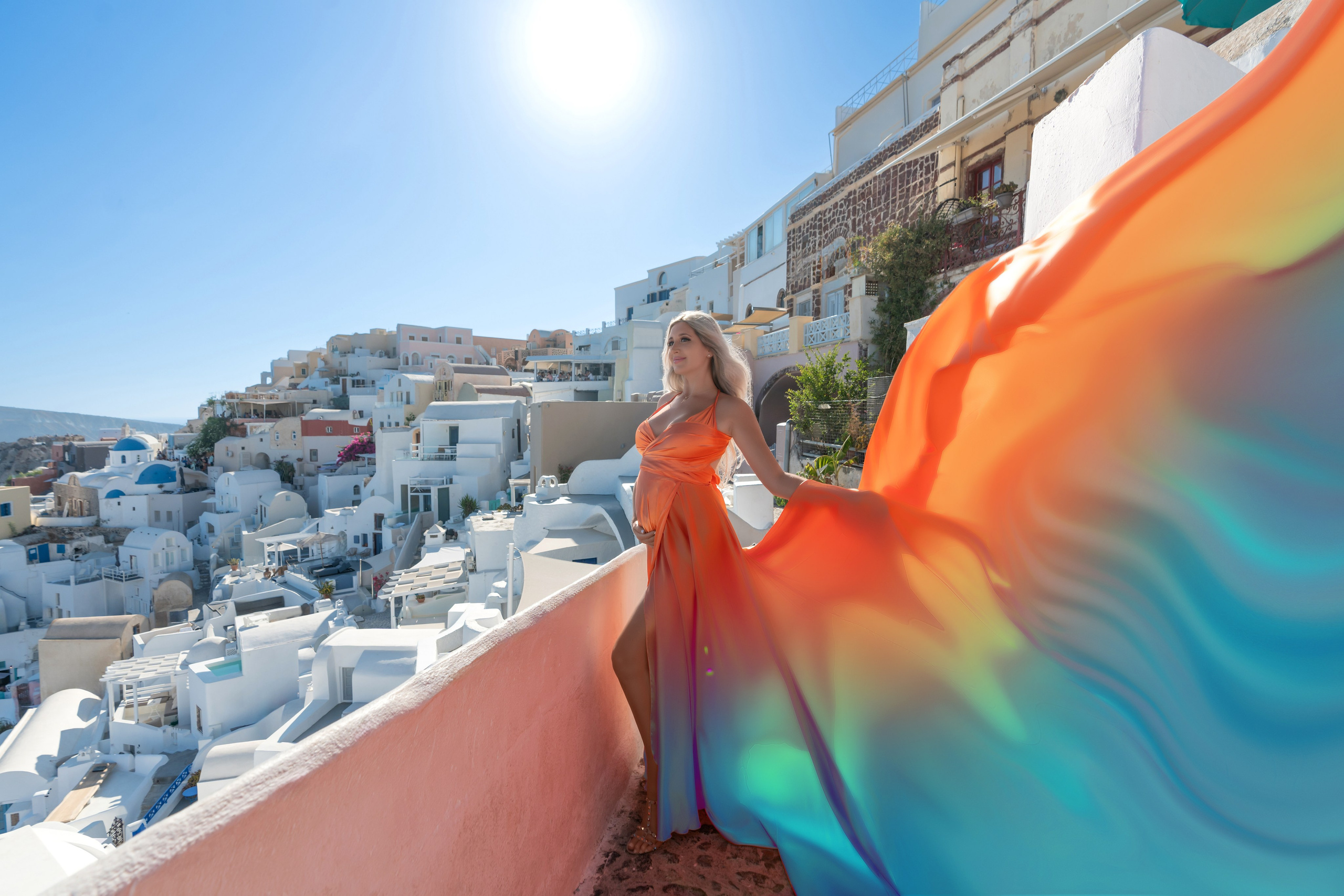 Séance Photo Maternité à Oia, Santorin: Rêve en Robe Volante Orange. Photographe vidéaste à Santorin|Séances photos de Robe volante Santorin|