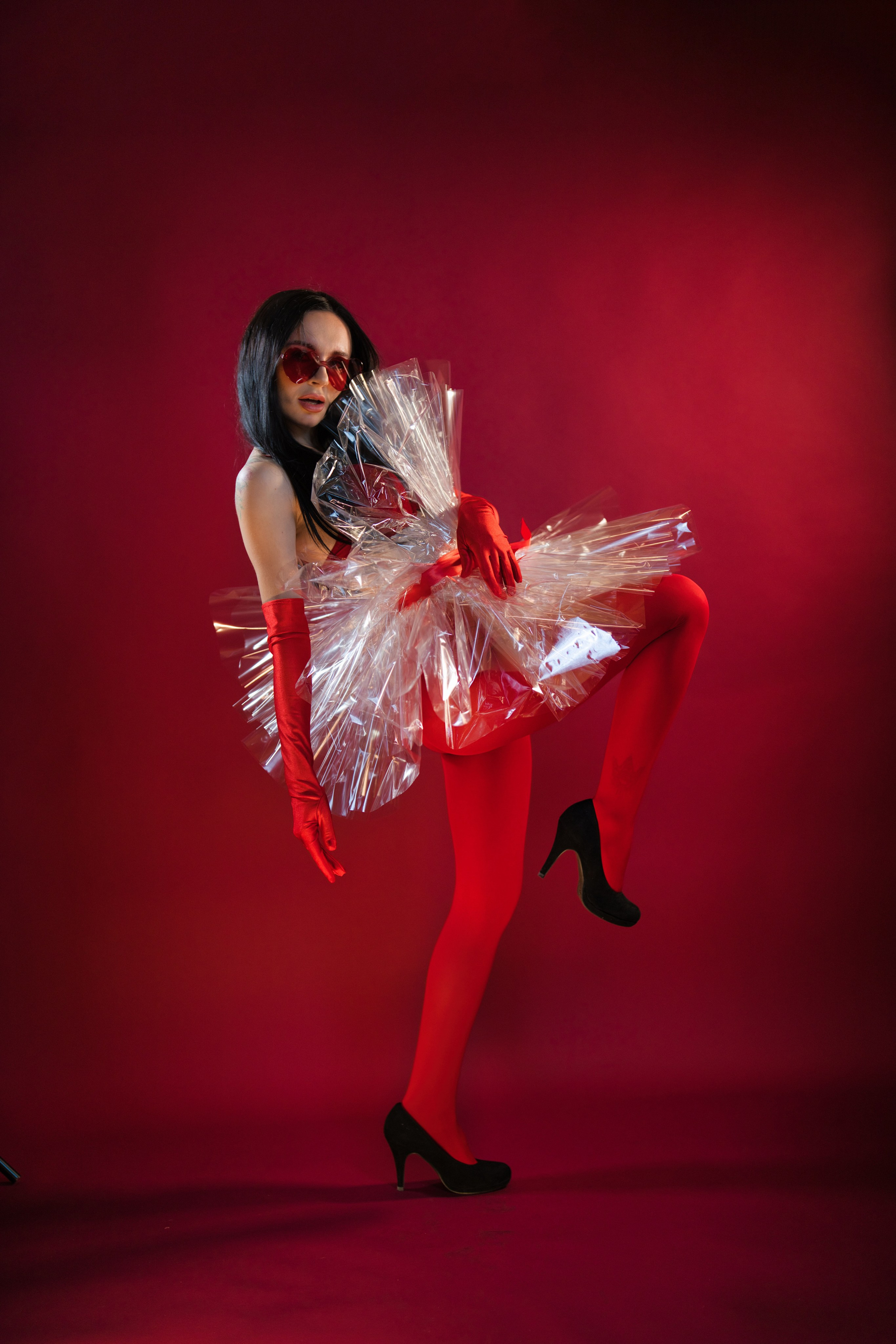 Frau posiert mit elegantem Kleid im Fotostudio auf bordeauxrotem Hintergrund.