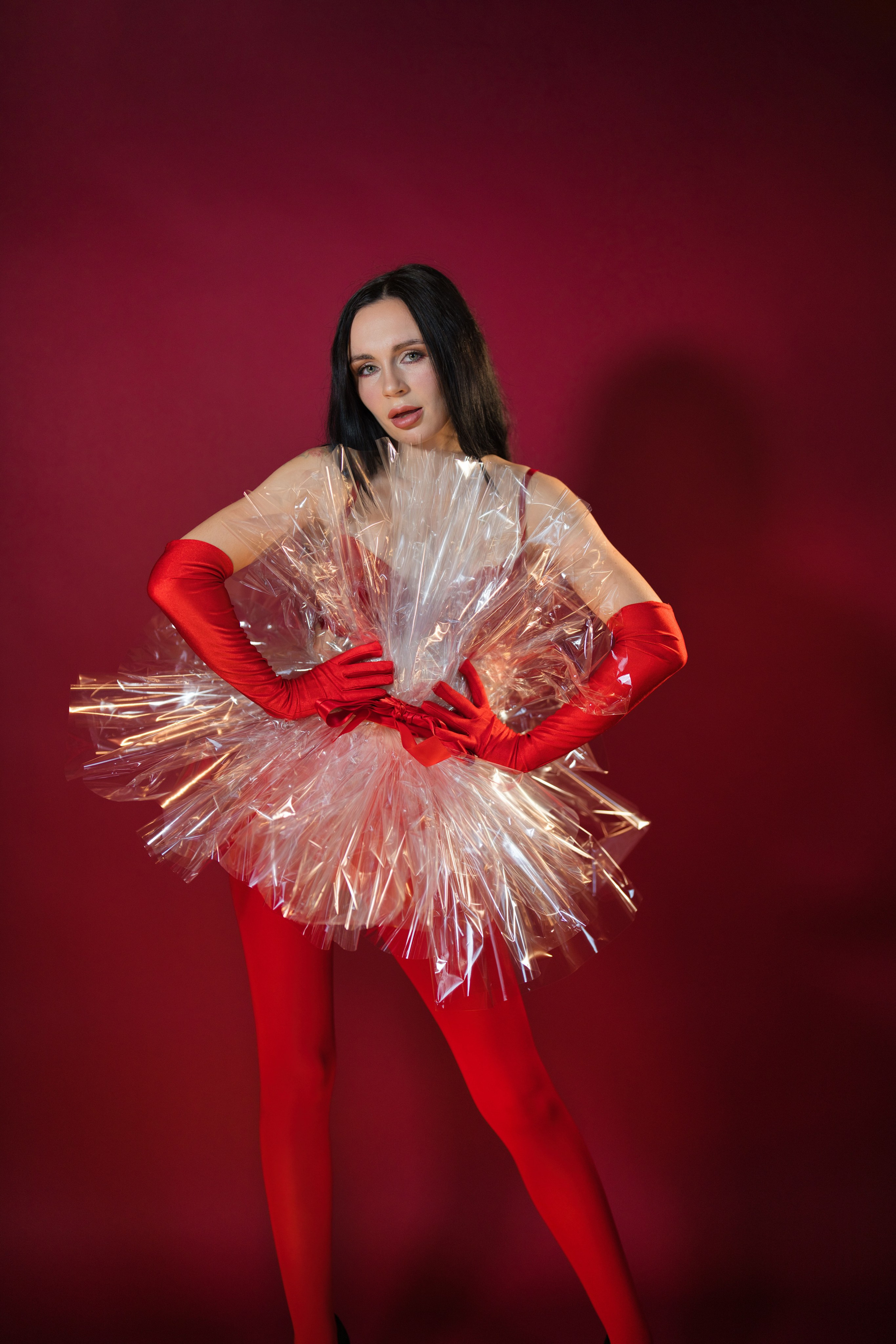 Frau in rotem Kleid posiert festlich vor Studiohintergrund.