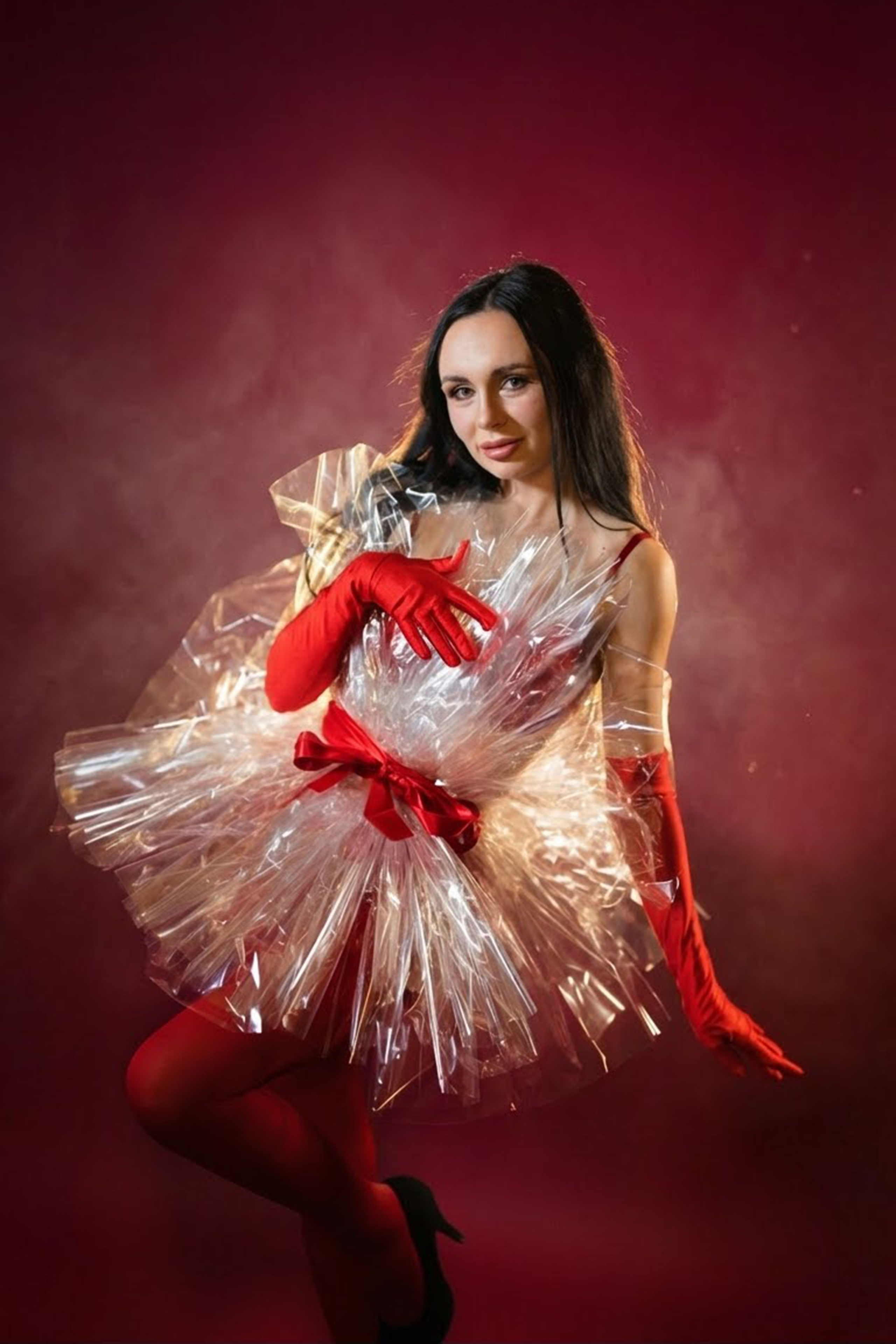 Frau in rotem Outfit posiert weihnachtlich vor bordeauxrotem Hintergrund.