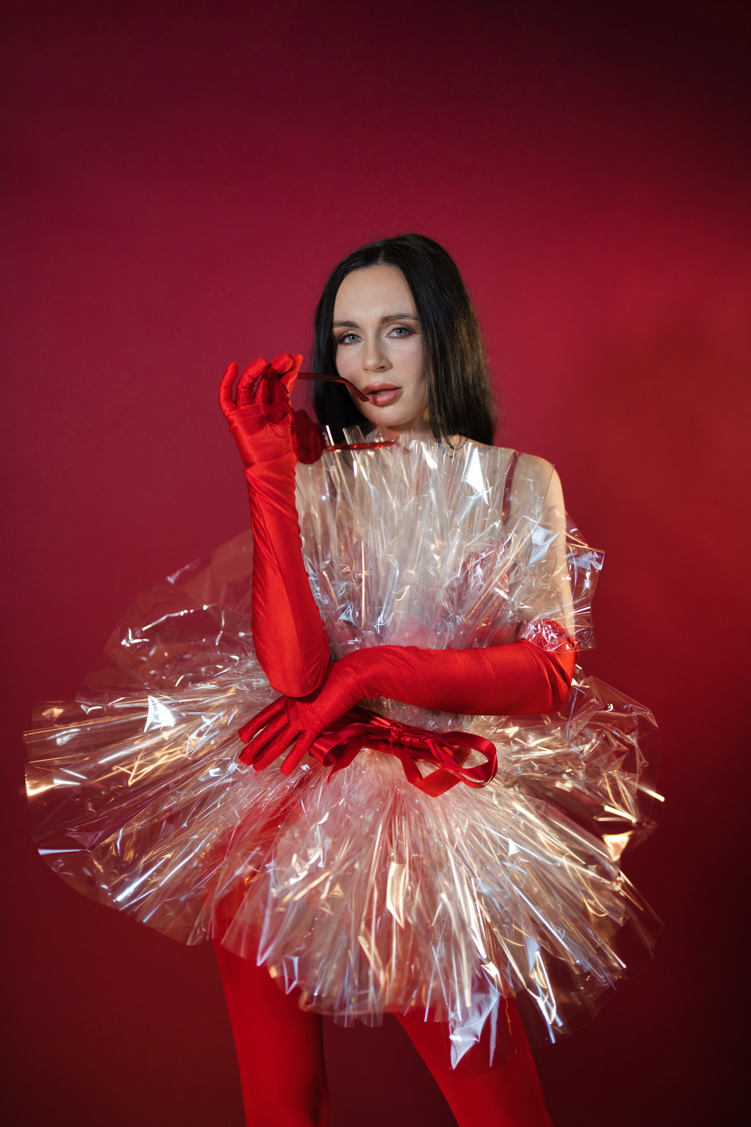 Frau hält glitzernde Federn vor rotem Hintergrund.