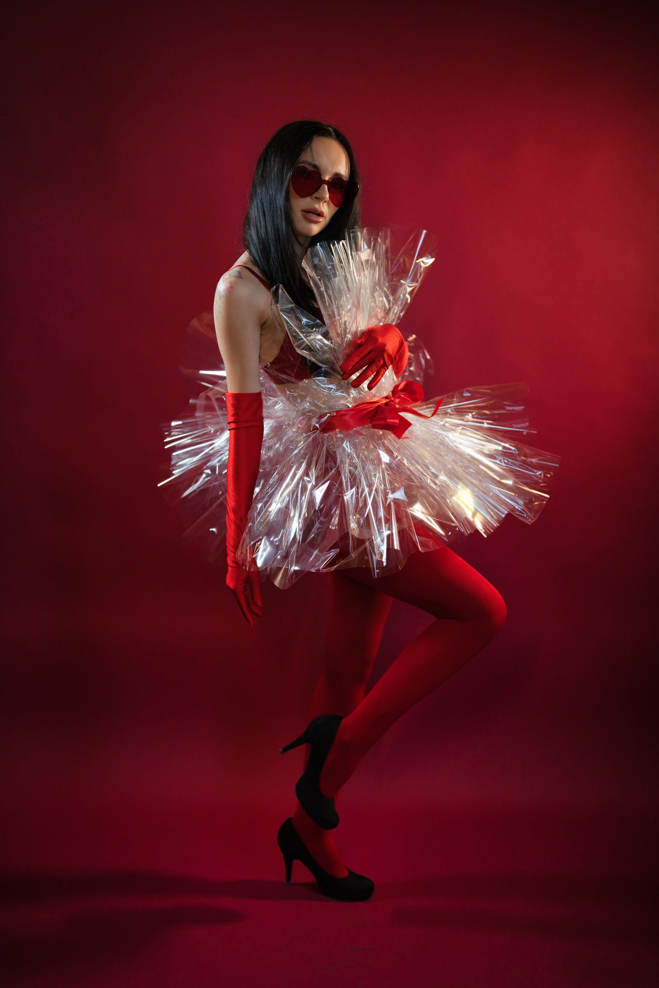 Frau sitzt auf einem Hocker im Weihnachtsoutfit vor dunkelrotem Hintergrund.