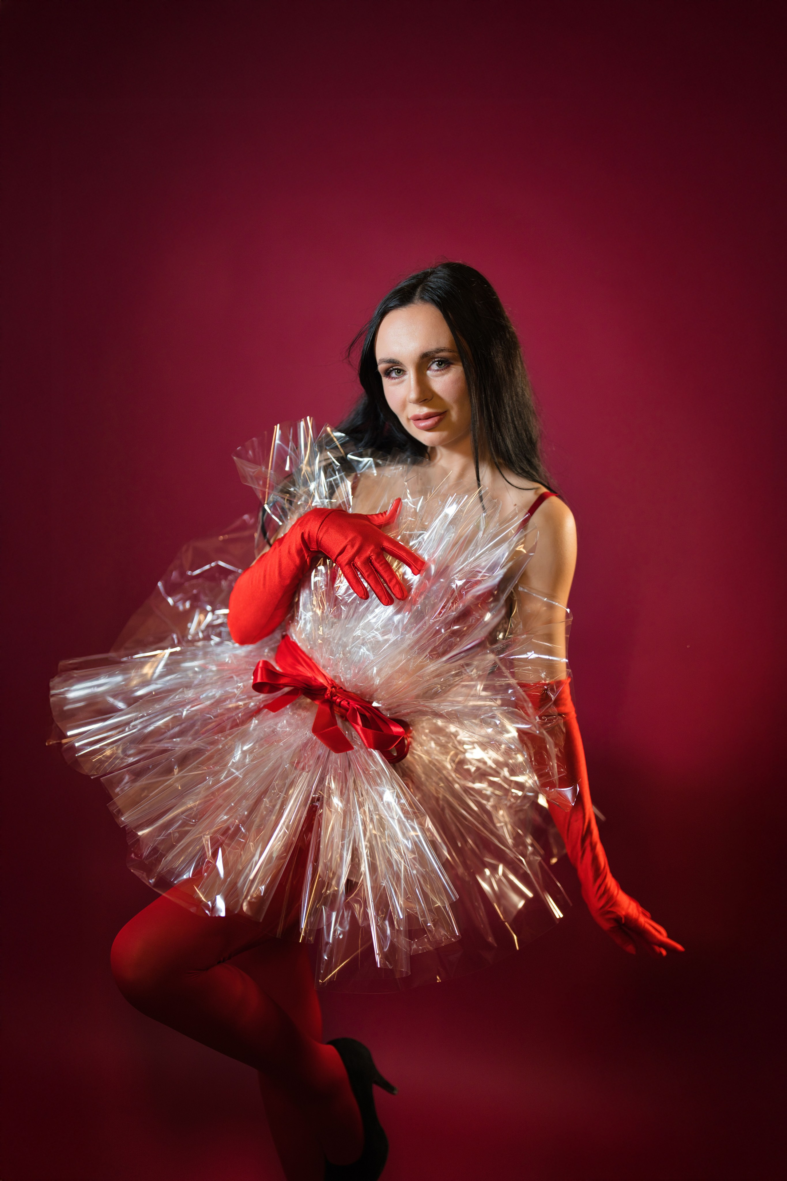 Halbporträt einer Frau mit festlichen Accessoires vor rotem Hintergrund.