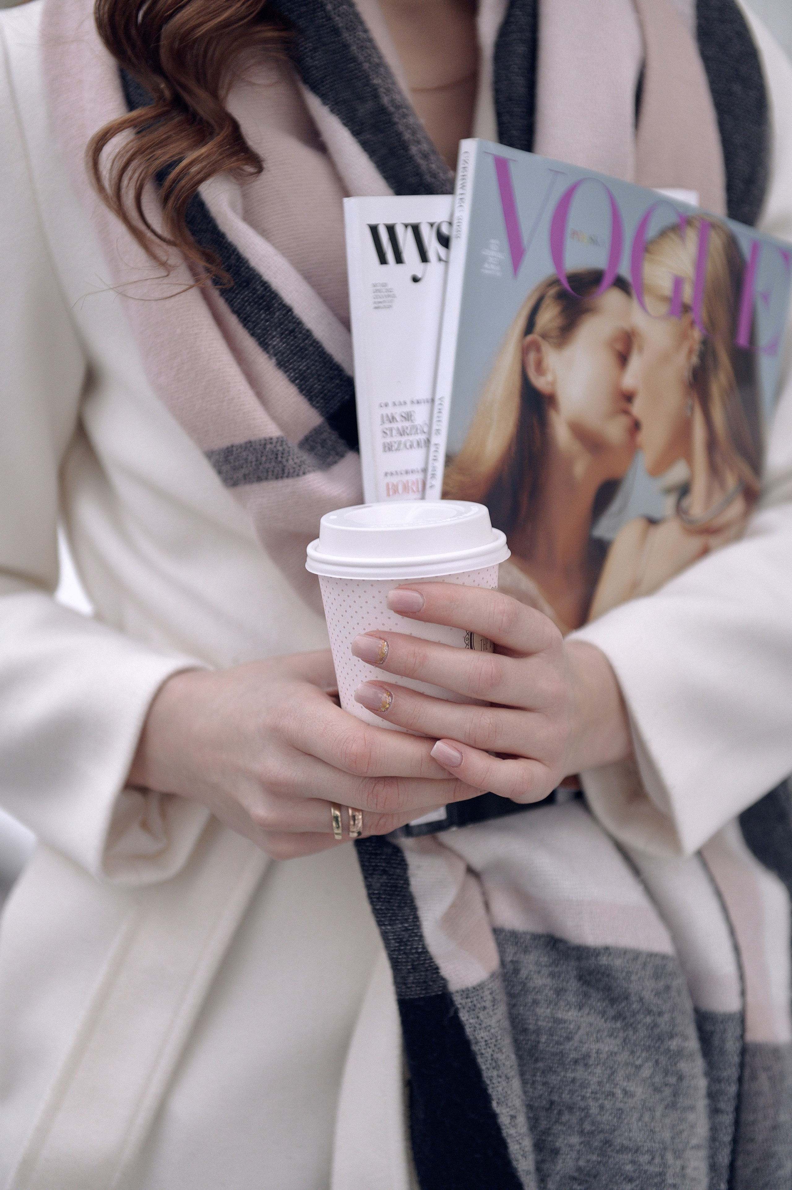 Zdjęcie detali, kubek z kawą w rękach oraz magazyn VOGUE