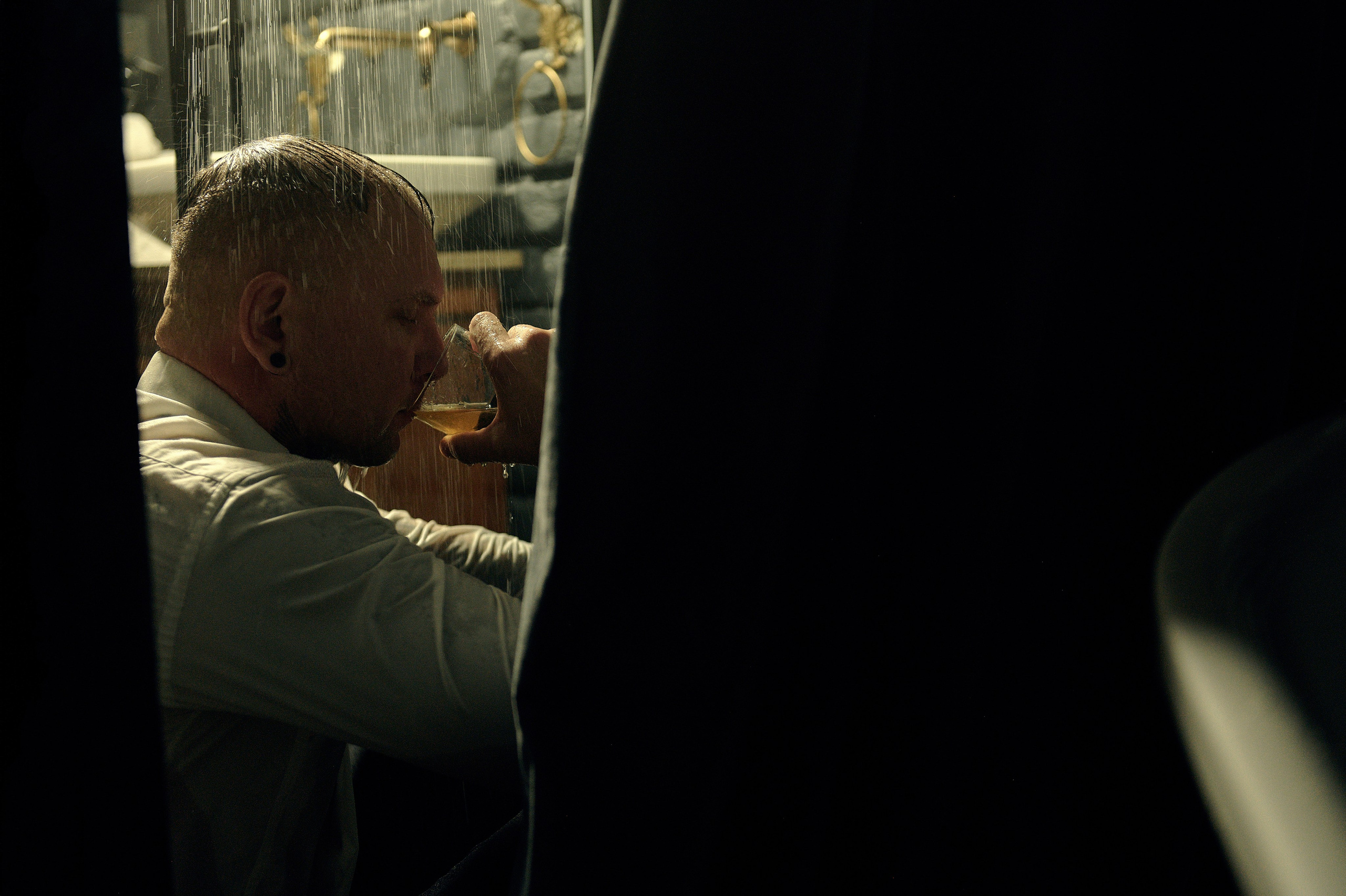 Zbliżenie – mężczyzna pije alkohol pod prysznicem