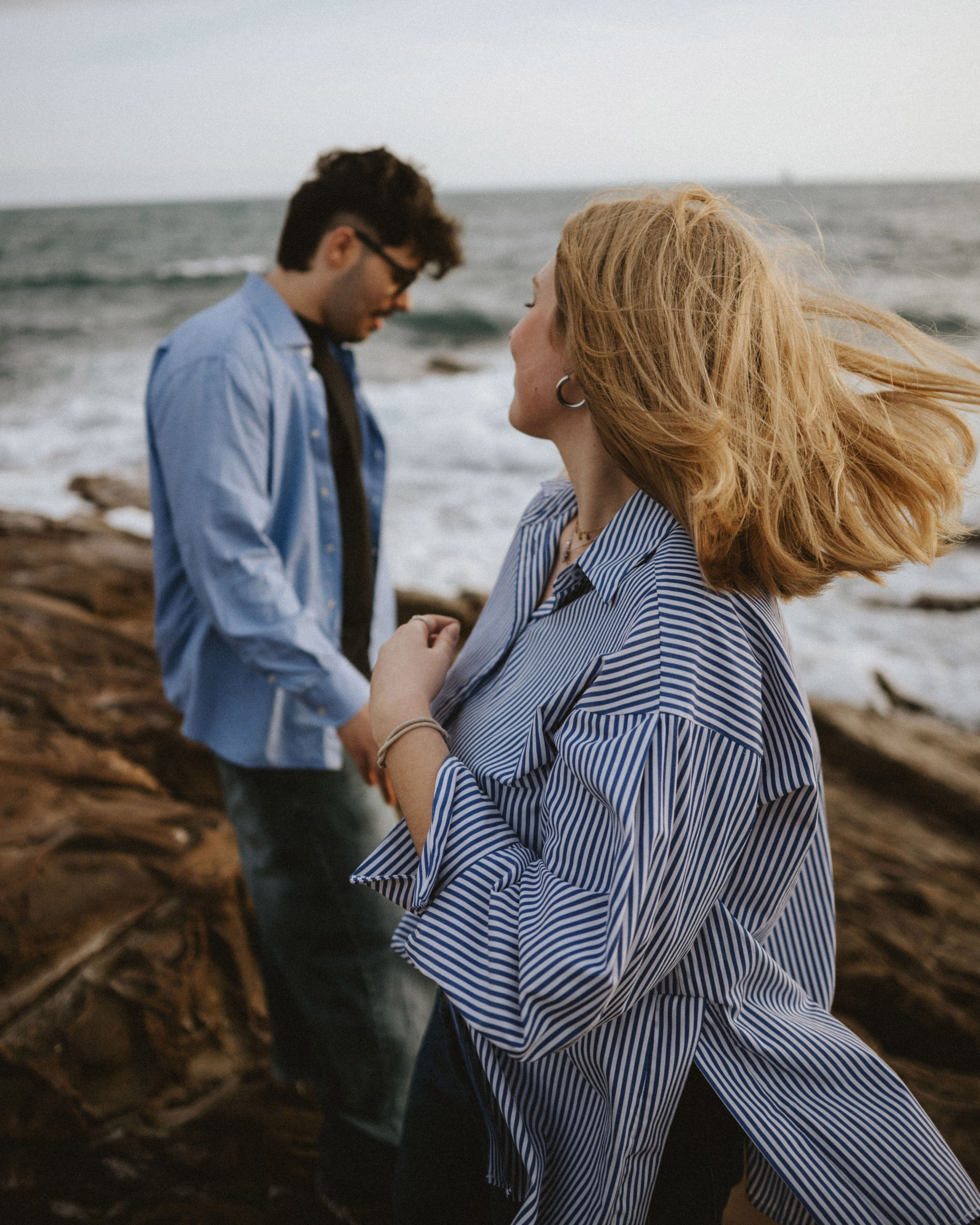 “The couple on the beach, their faces turned in different directions, with the woman’s hair blowing in the wind.”
