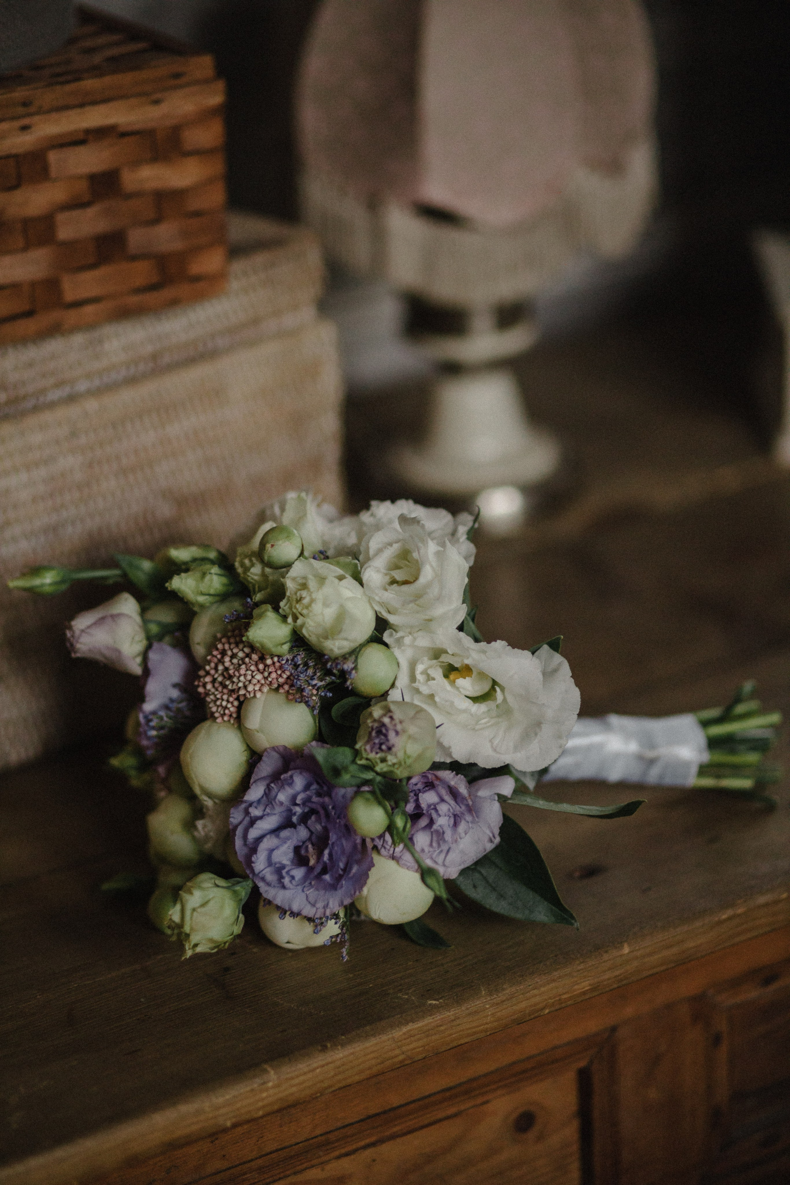 Close-up of wedding rings and soft floral bouquet on rustic table