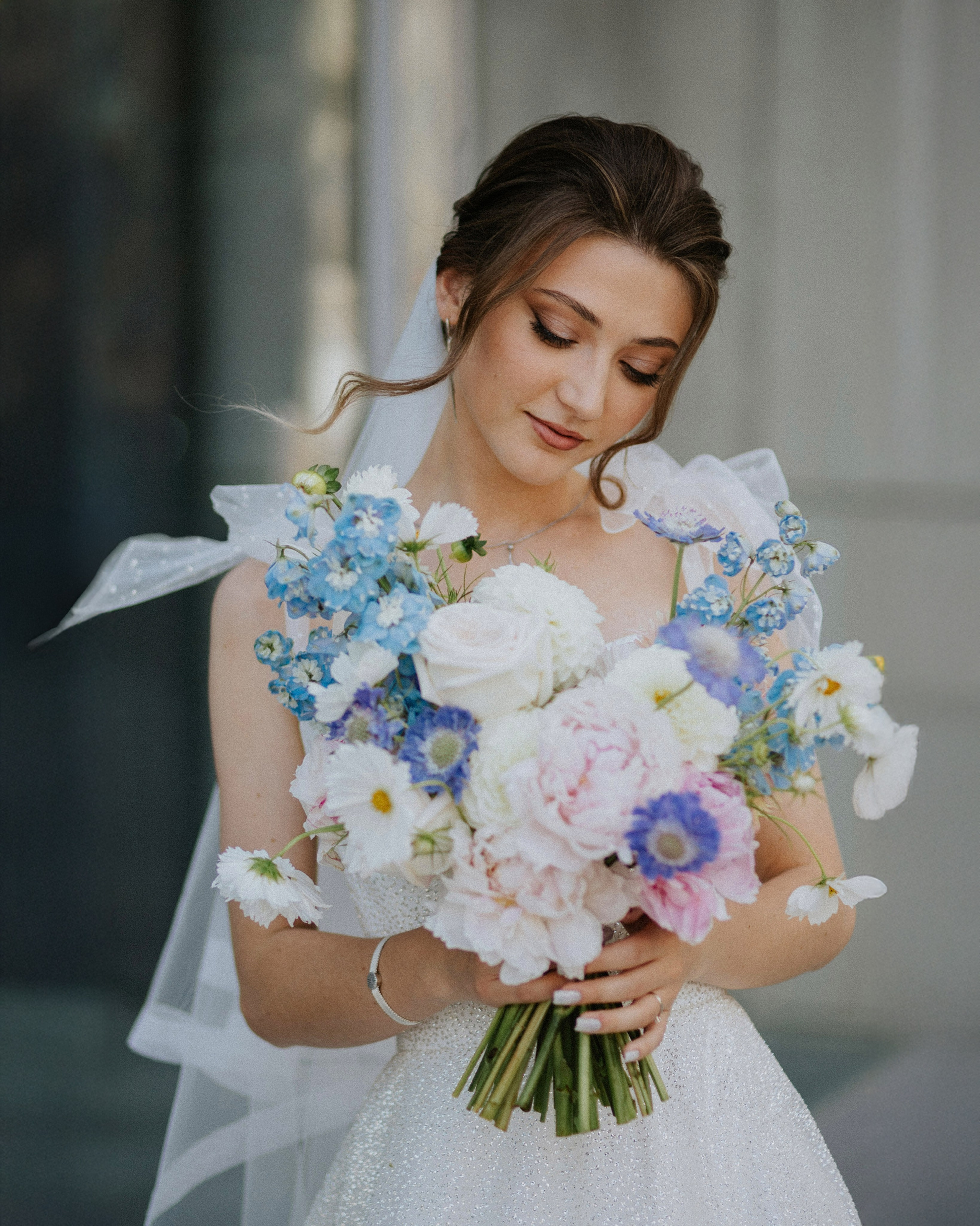 “The bride with a bouquet of roses, peonies, and blue flowers, against the backdrop of elegant architecture, a wedding in Rome or Venice.”