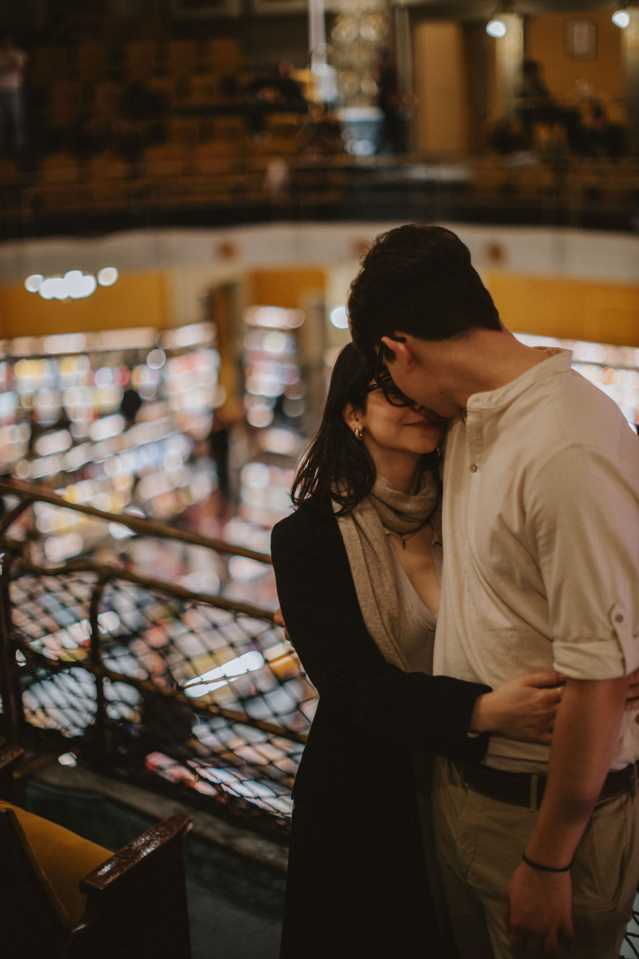 “Una coppia abbracciata in un'accogliente libreria, con gli scaffali sfocati sullo sfondo”.