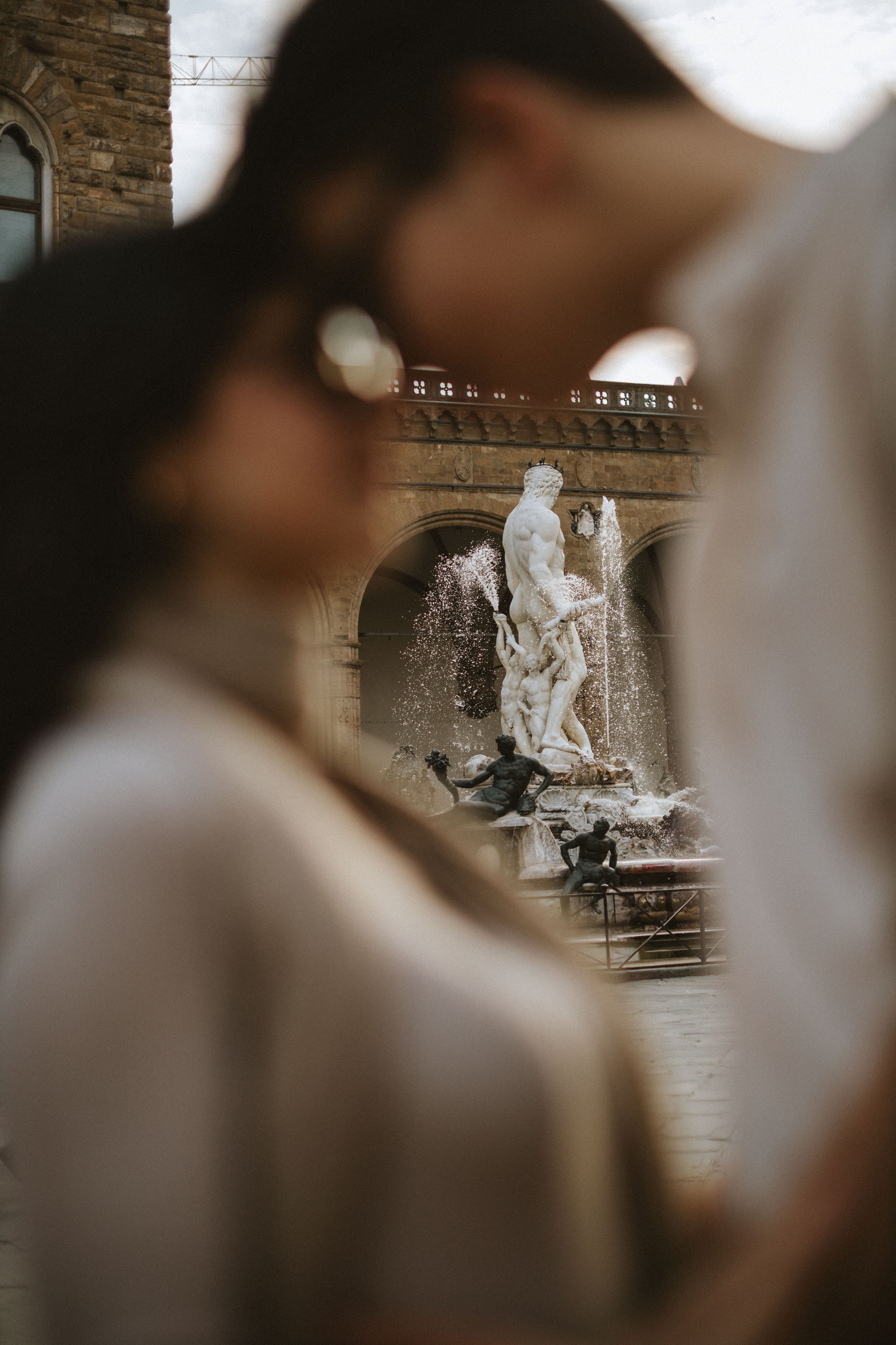 “Un momento sfocato di affetto tra una coppia con una bella fontana sullo sfondo”.