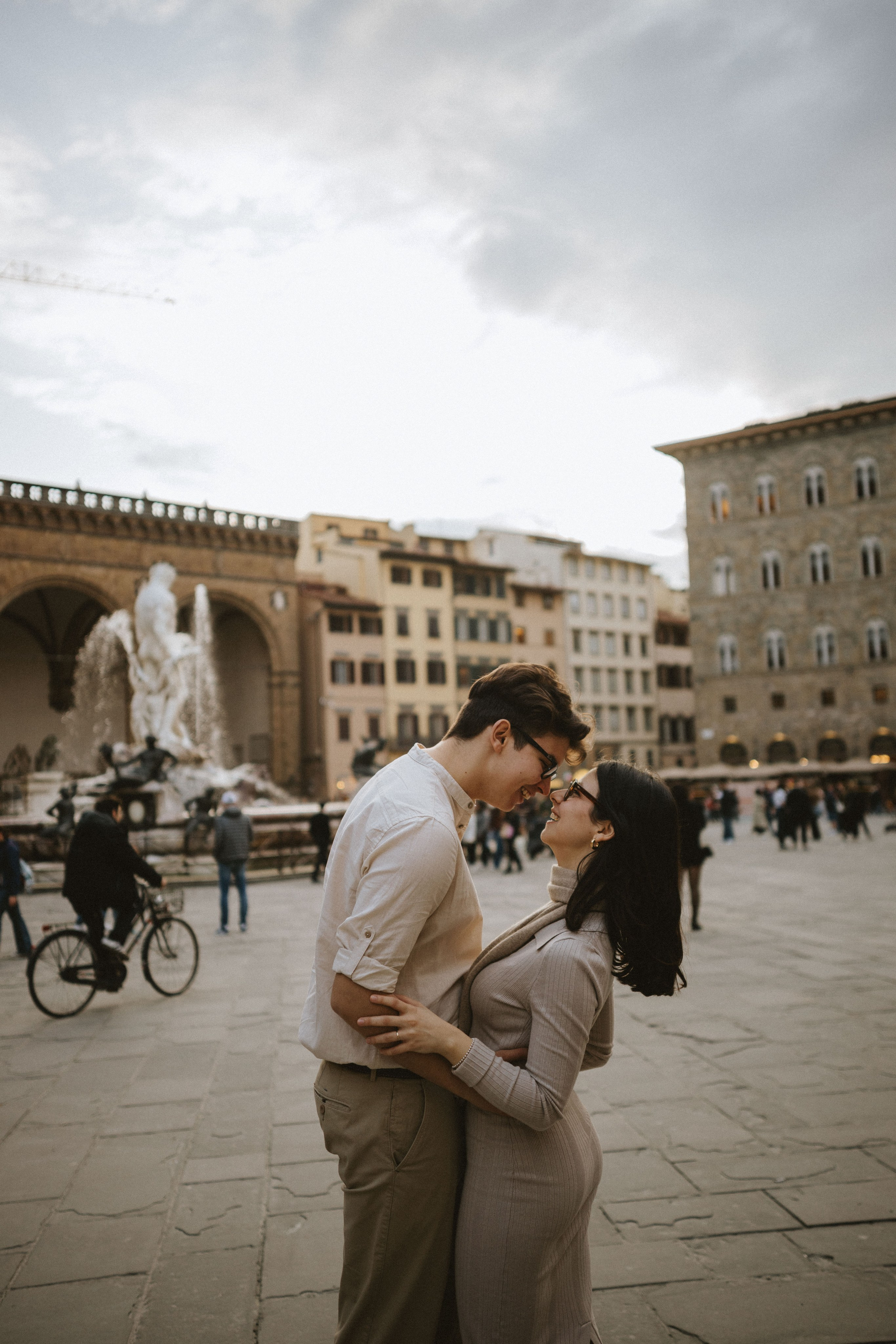 “Una coppia abbracciata nella piazza, con la famosa fontana e gli edifici storici sullo sfondo”.