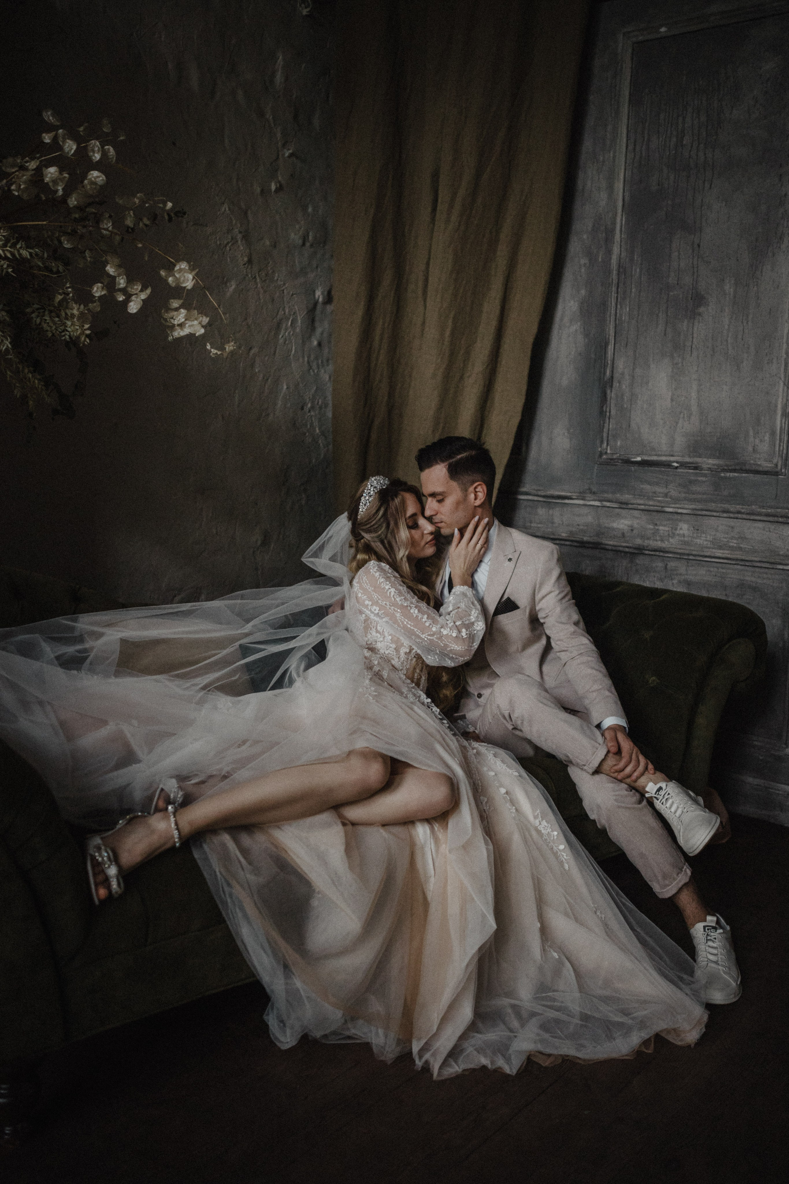 “Una splendida immagine in bianco e nero di una sposa in un abito da sposa fluente, in piedi su una scalinata con il velo che si dispiega drammaticamente dietro di lei nel vento. Tiene un bouquet in una mano e il tessuto del velo crea una silhouette a forma di cuore sullo sfondo scuro di un edificio moderno”.