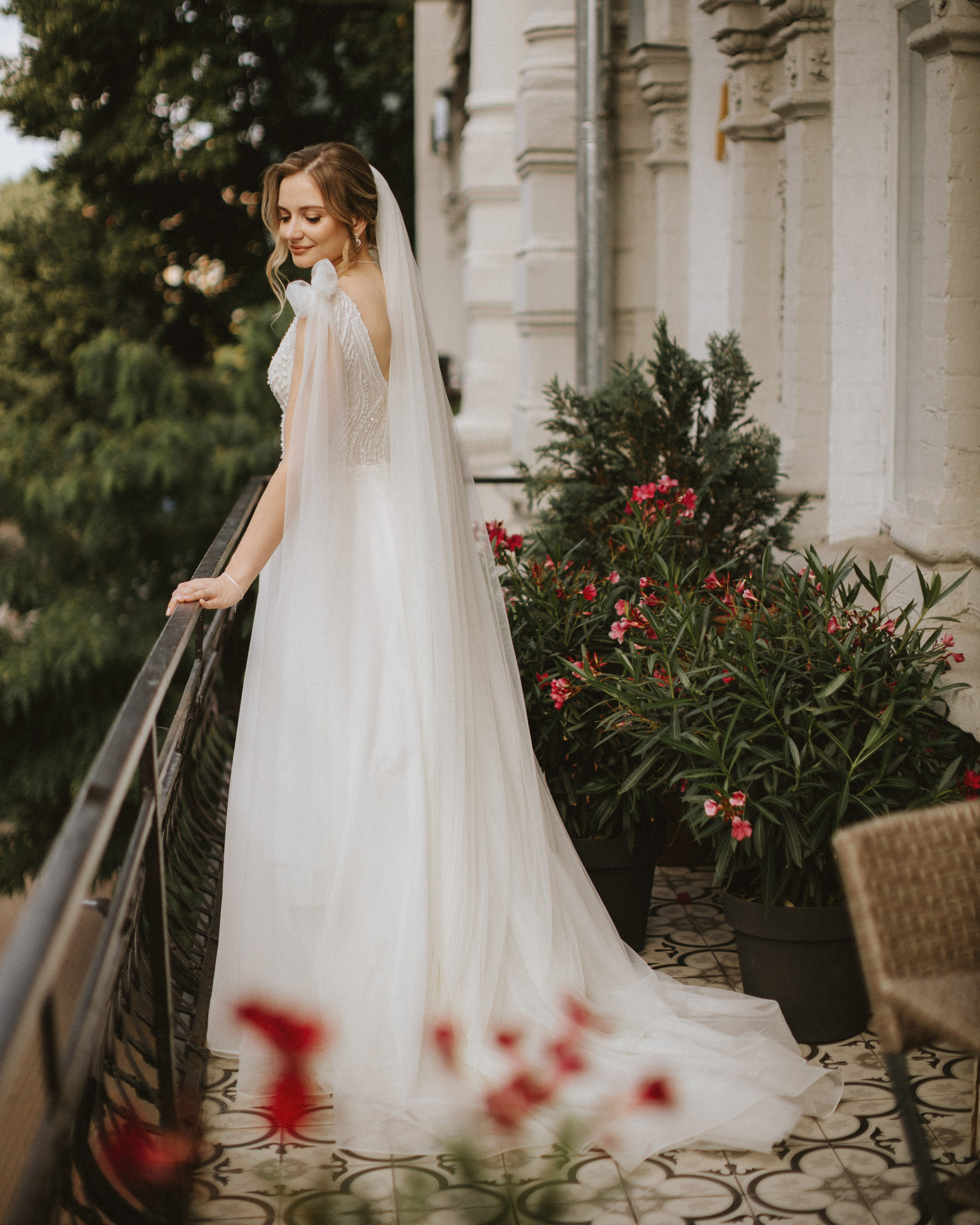 “The bride on the balcony in a wedding dress with a veil, surrounded by flowers, a wedding in one of Italy’s picturesque cities, such as Verona or Portofino.”
