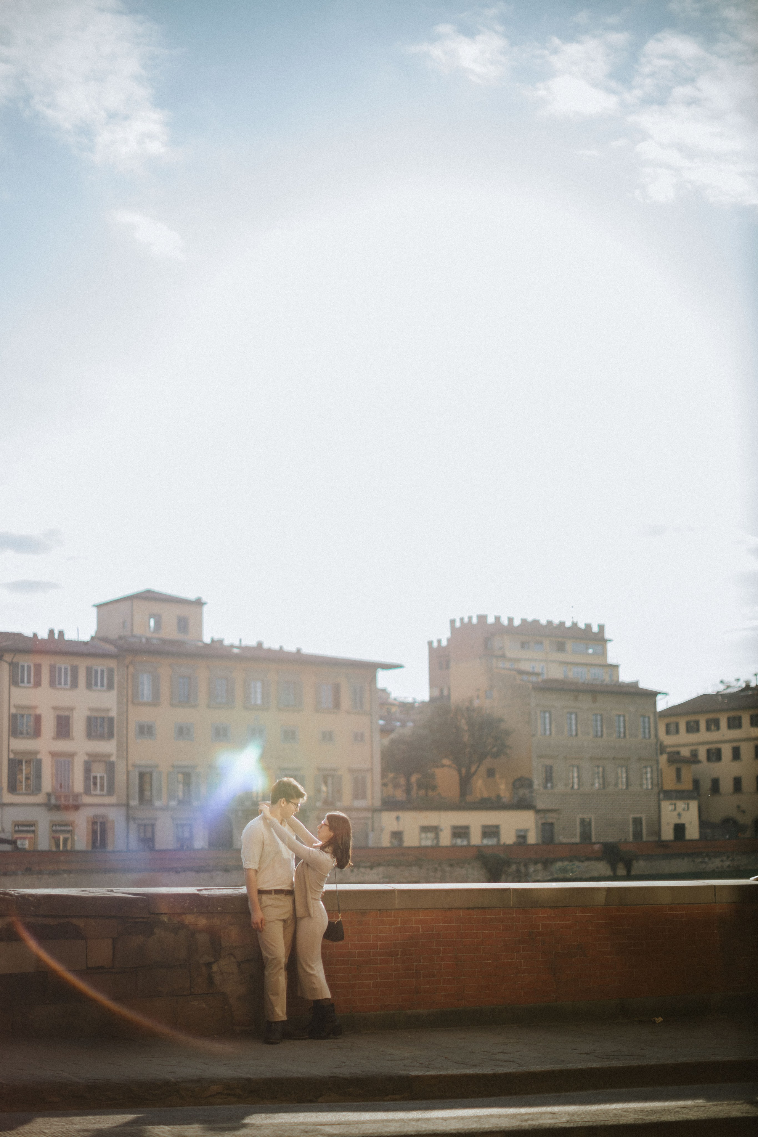“Una coppia che condivide un momento di tenerezza in una bella strada fiorentina, con la calda luce del sole che li circonda”.