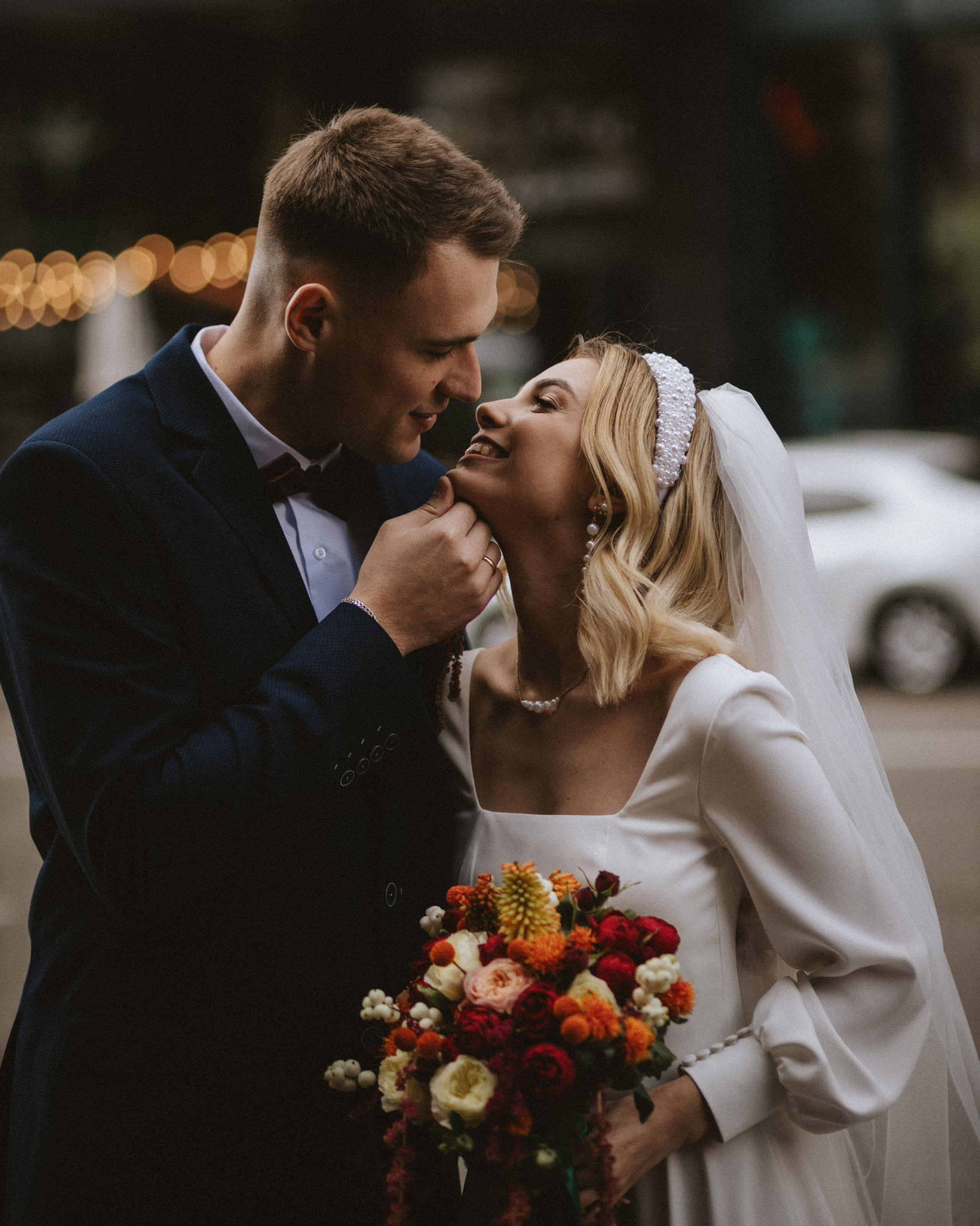 “The bride holding a bouquet and the groom in elegant attire enjoying the moment on the street in Italy, possibly in Milan or Rome, exchanging a tender look.”
