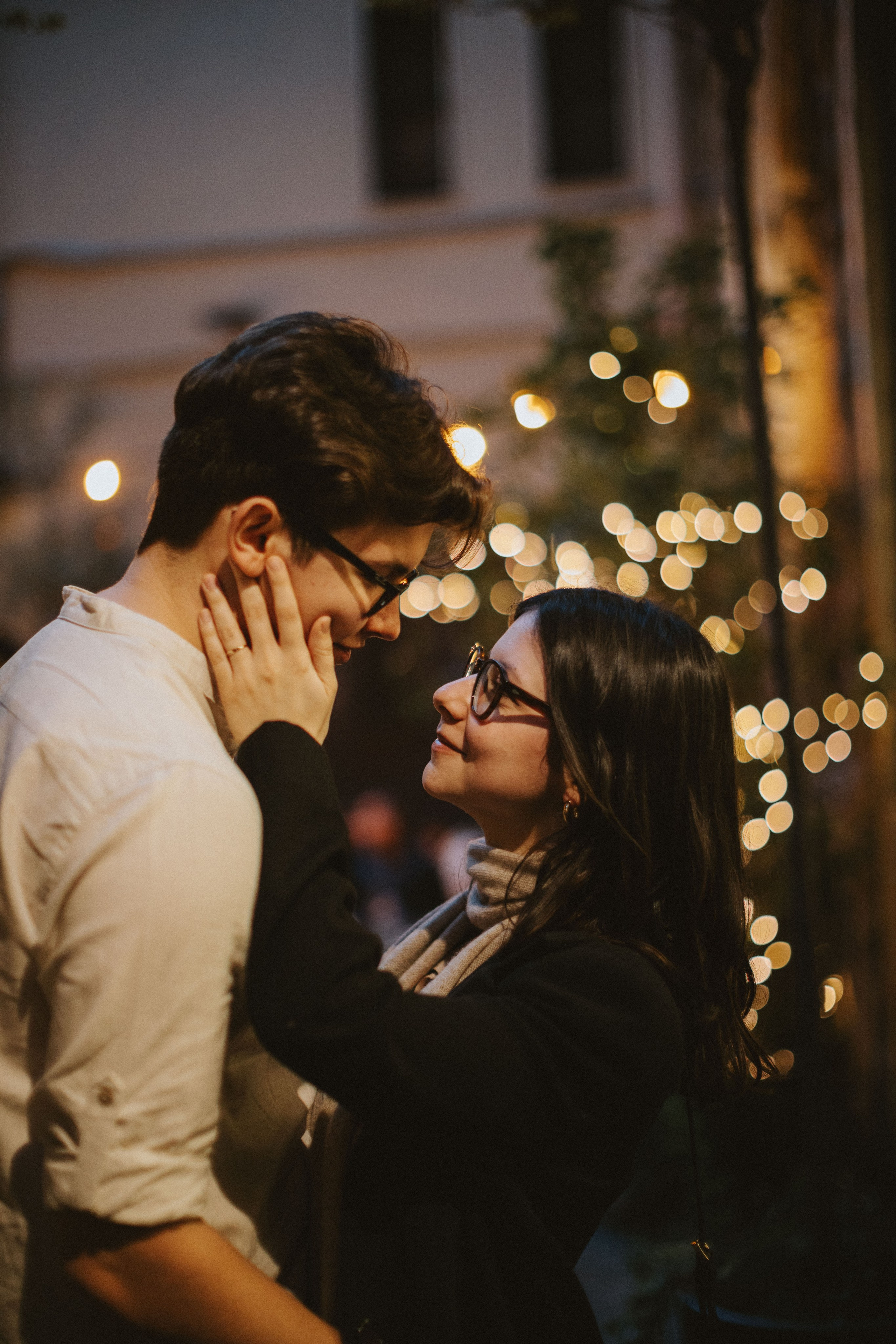 “Una coppia condivide un momento di tenerezza sotto luci soffuse e luminose, guardandosi amorevolmente”.